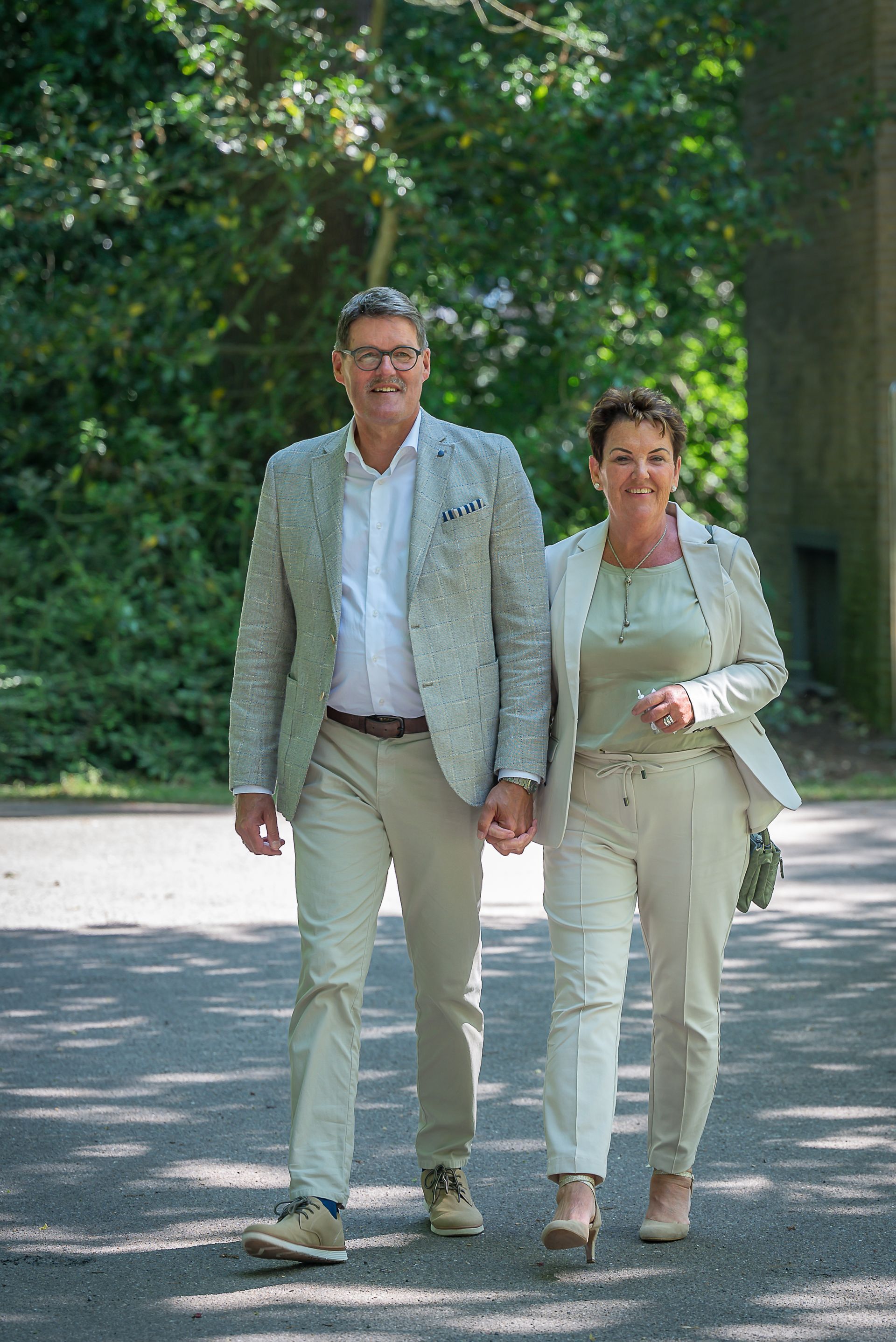 Een man en een vrouw lopen hand in hand over de weg.
