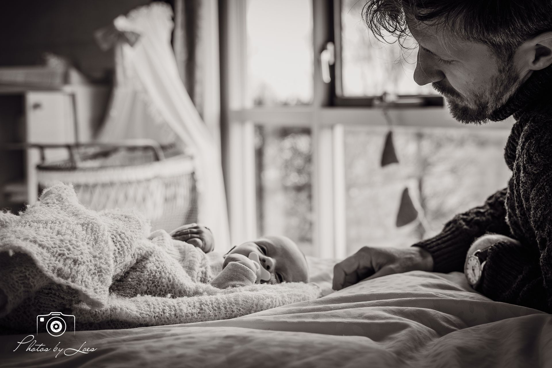 Een man ligt op een bed naast een pasgeboren baby.