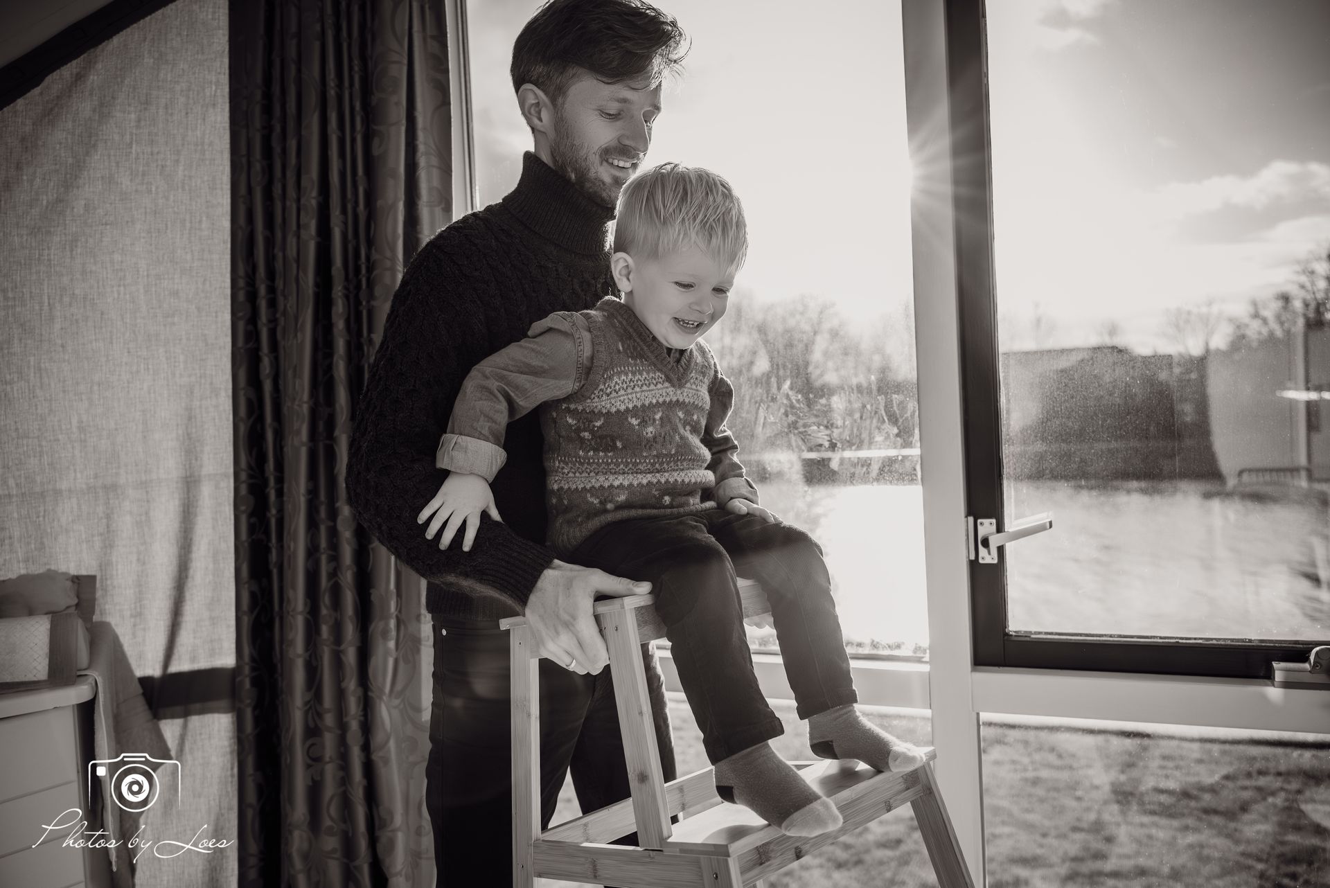 Een man houdt een jongetje vast dat op een schommelstoel zit.