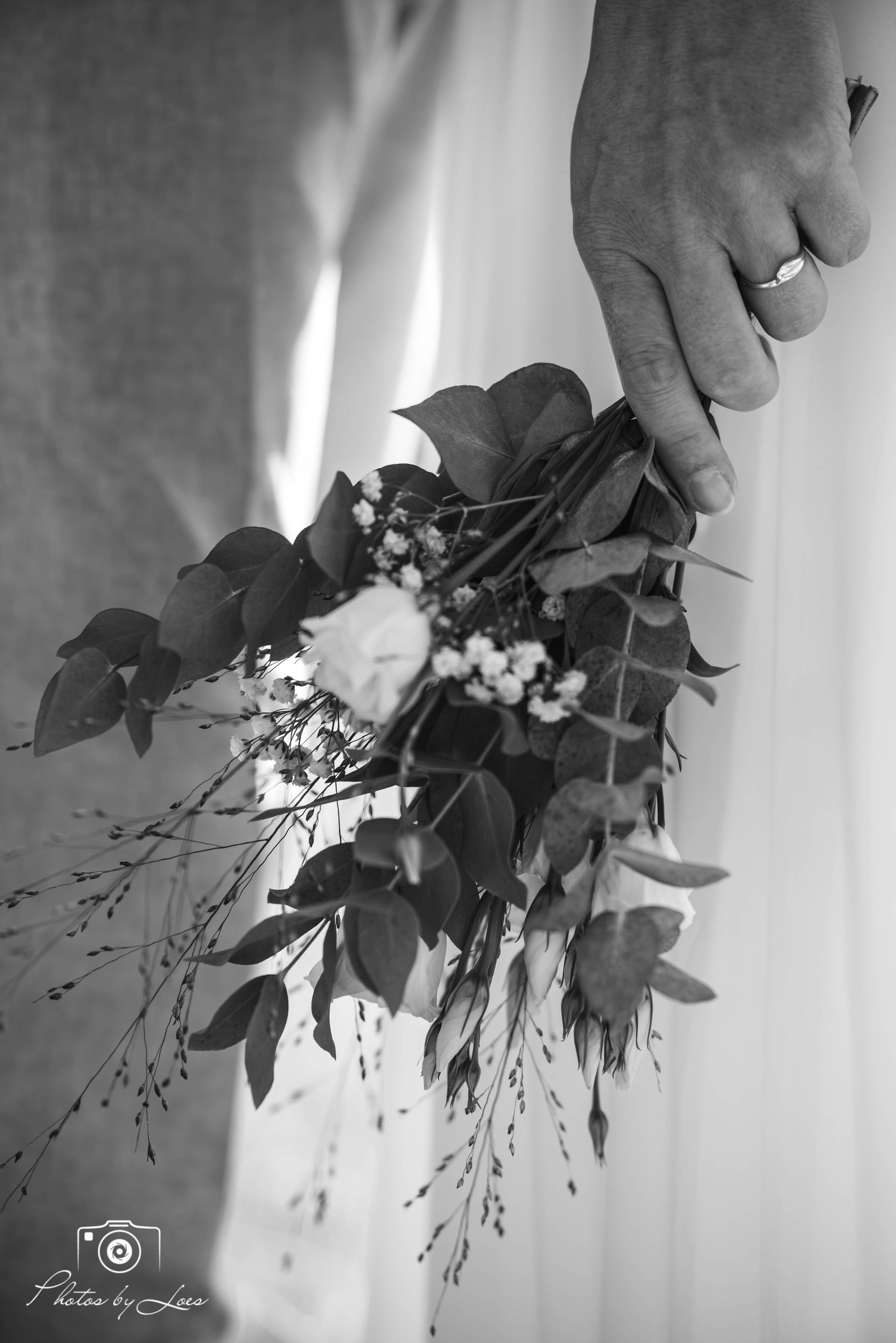 Een zwart-witfoto van een persoon die een boeket bloemen vasthoudt.