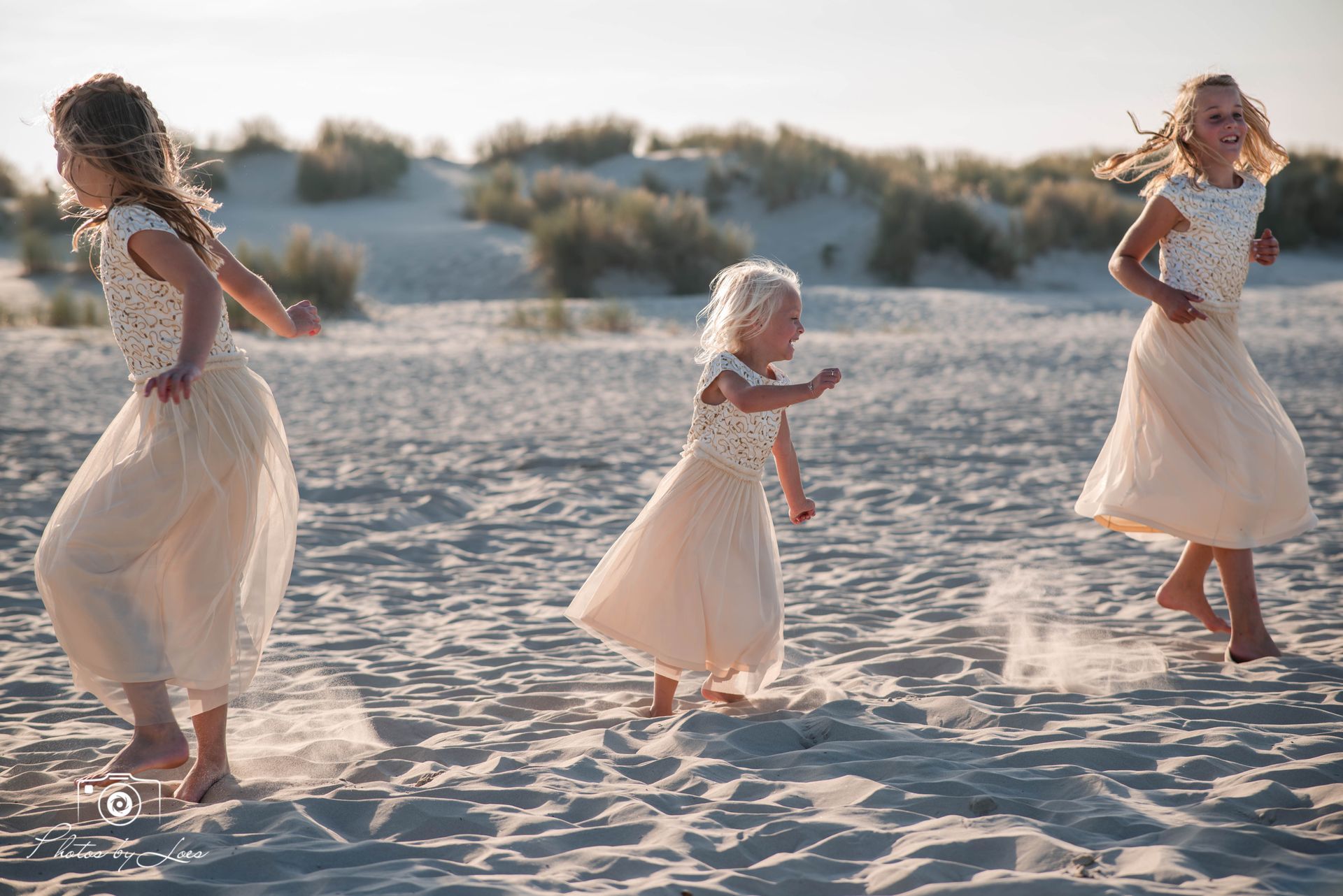Drie kleine meisjes rennen op het strand.