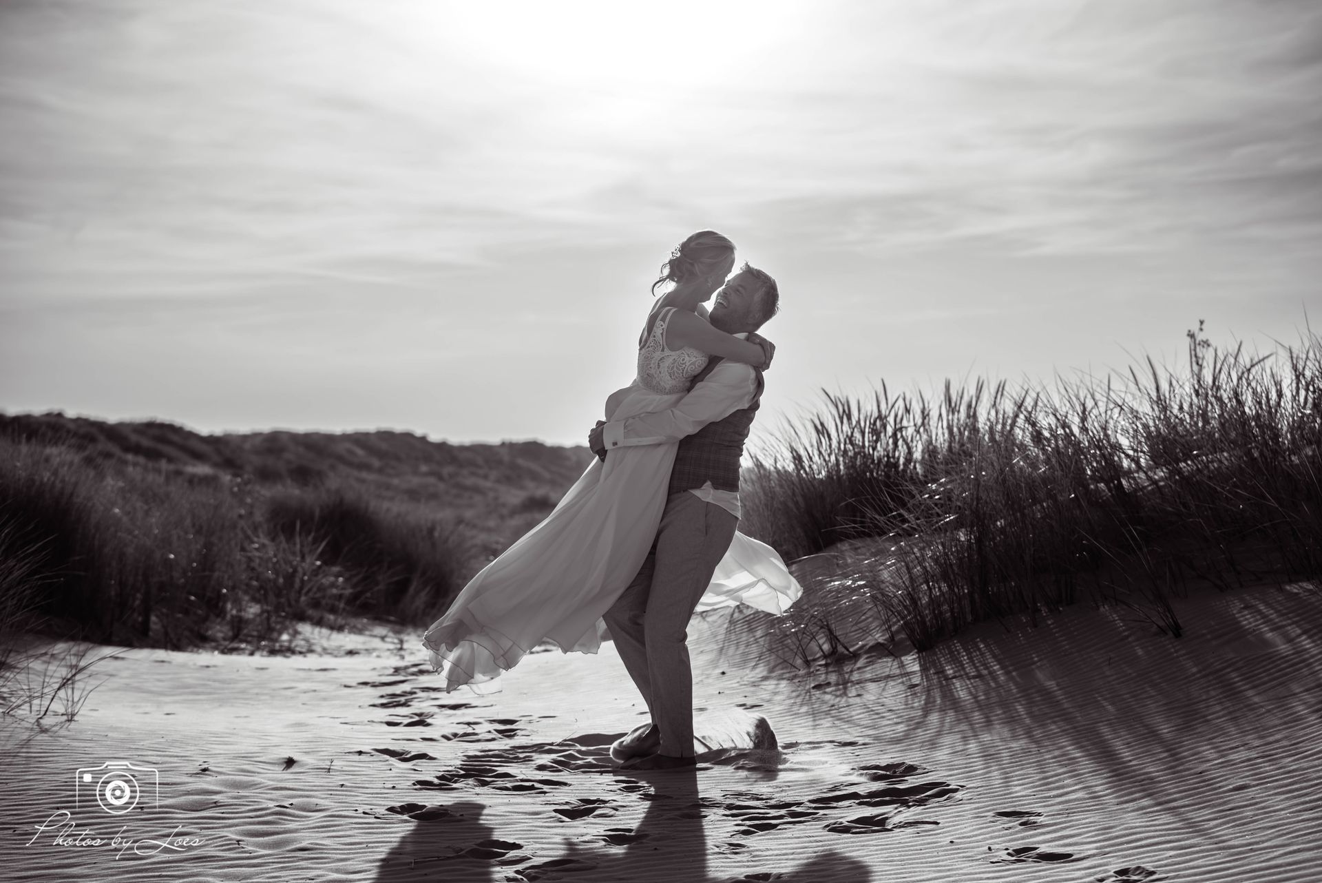 Een man houdt een vrouw in zijn armen op het strand.