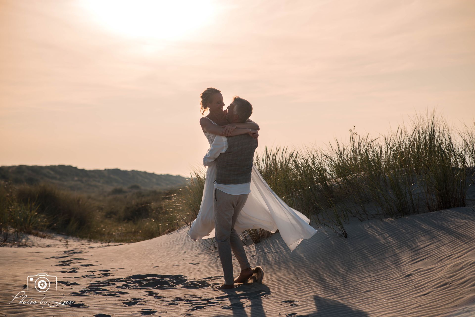 Een man houdt een vrouw in zijn armen op het strand.