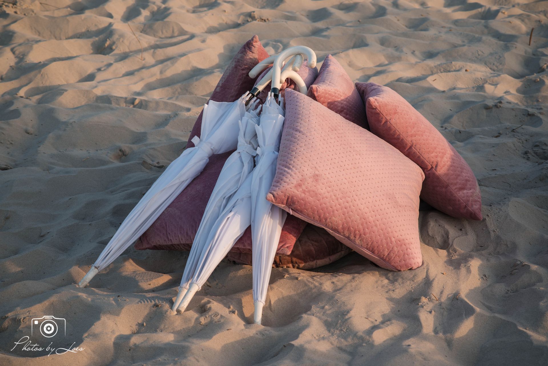 Een stapel kussens en parasols op een zandstrand