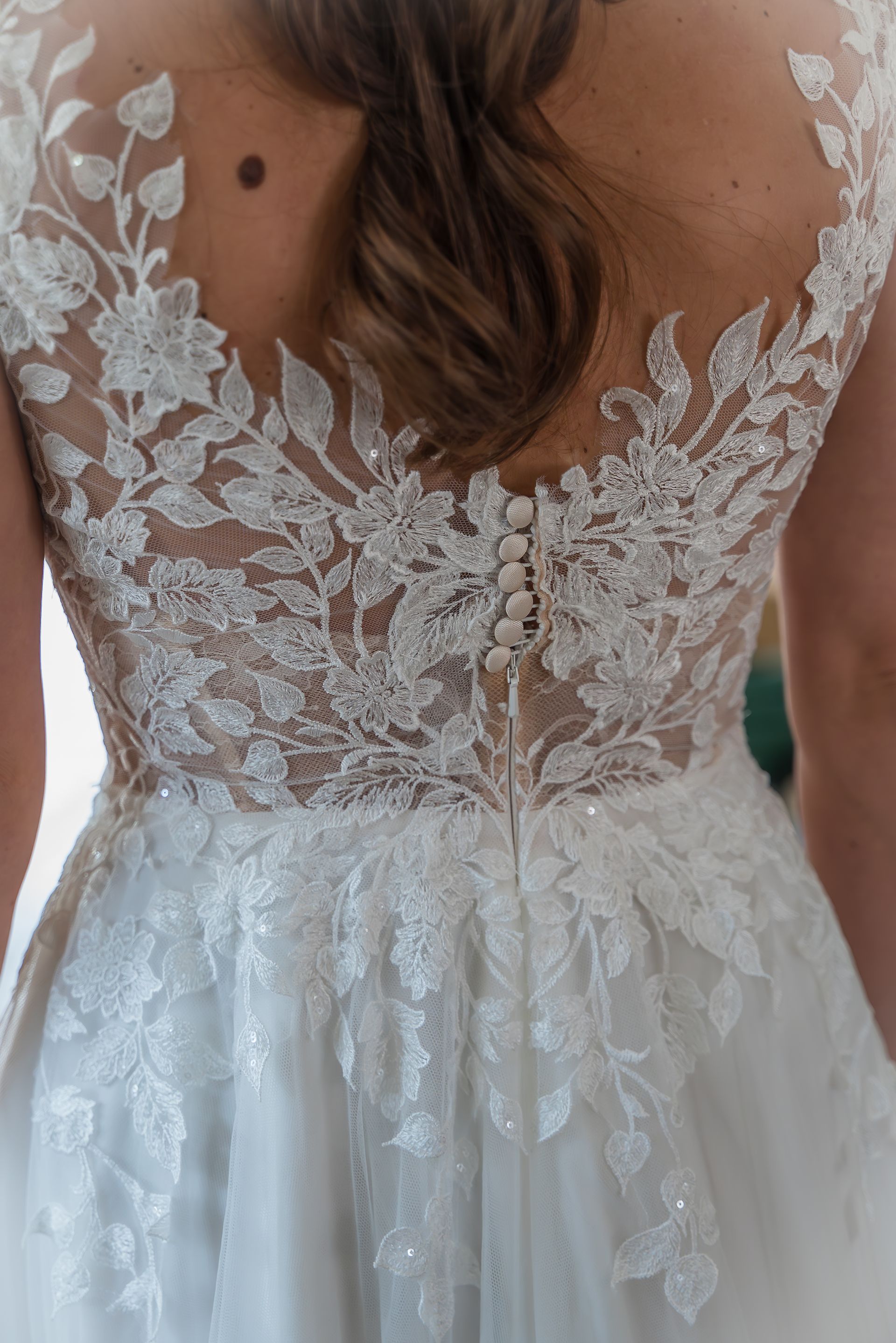 De rug van een vrouw die een witte kanten trouwjurk draagt.