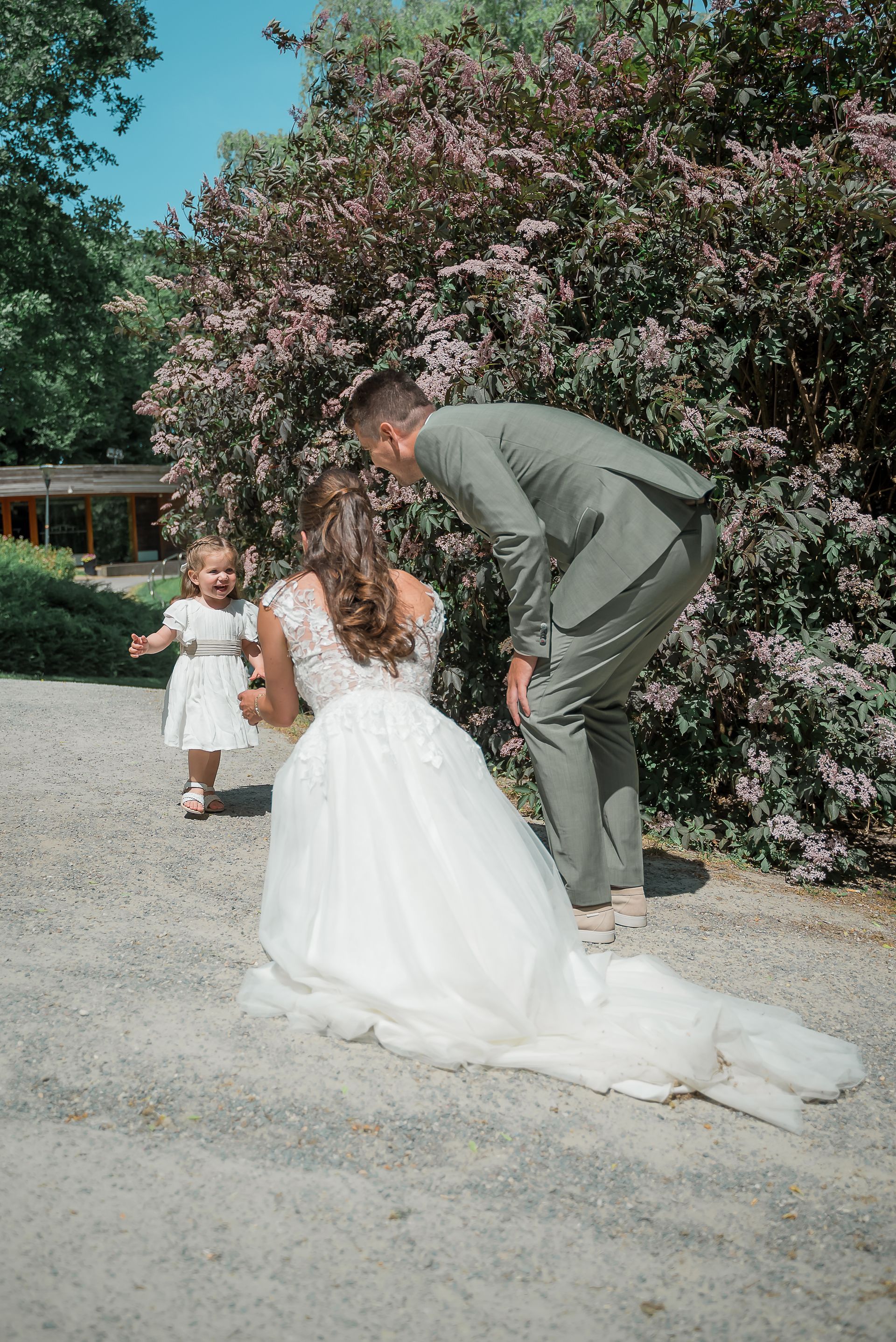 Een bruid en bruidegom poseren voor een foto met een bloemenmeisje.
