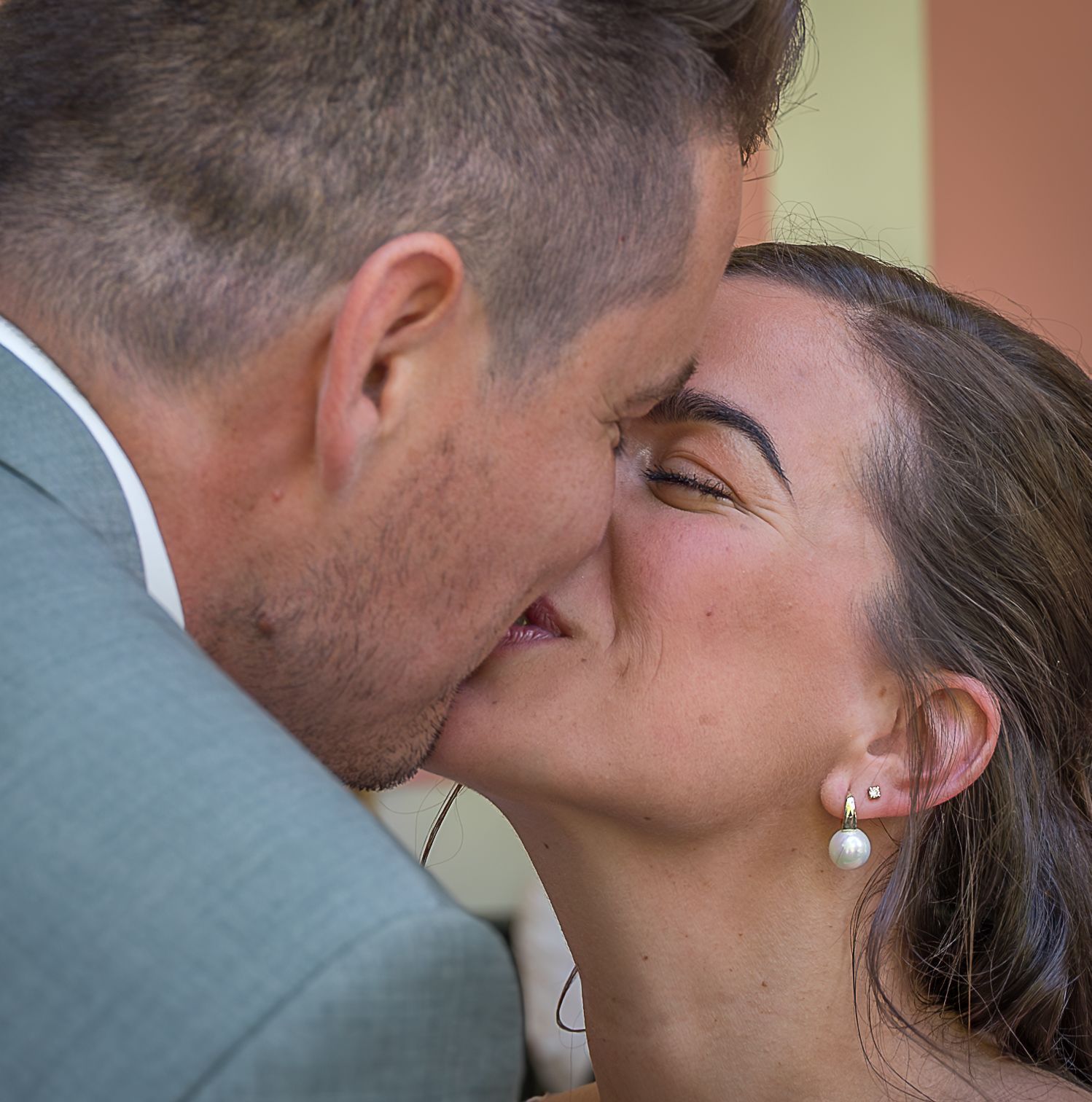 Een man en een vrouw kussen elkaar en de vrouw draagt ​​pareloorbellen.