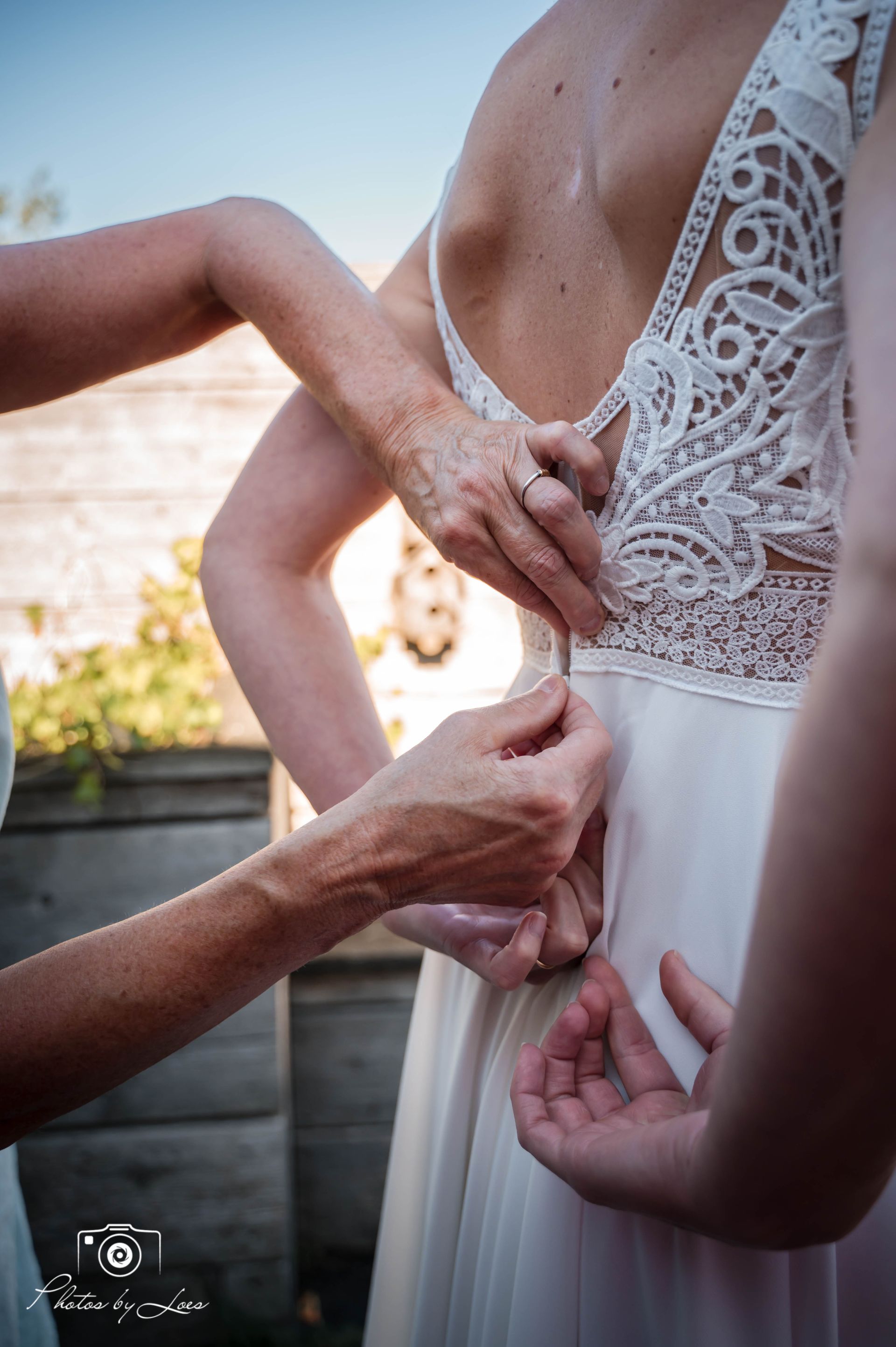 Een vrouw helpt een andere vrouw met haar trouwjurk.