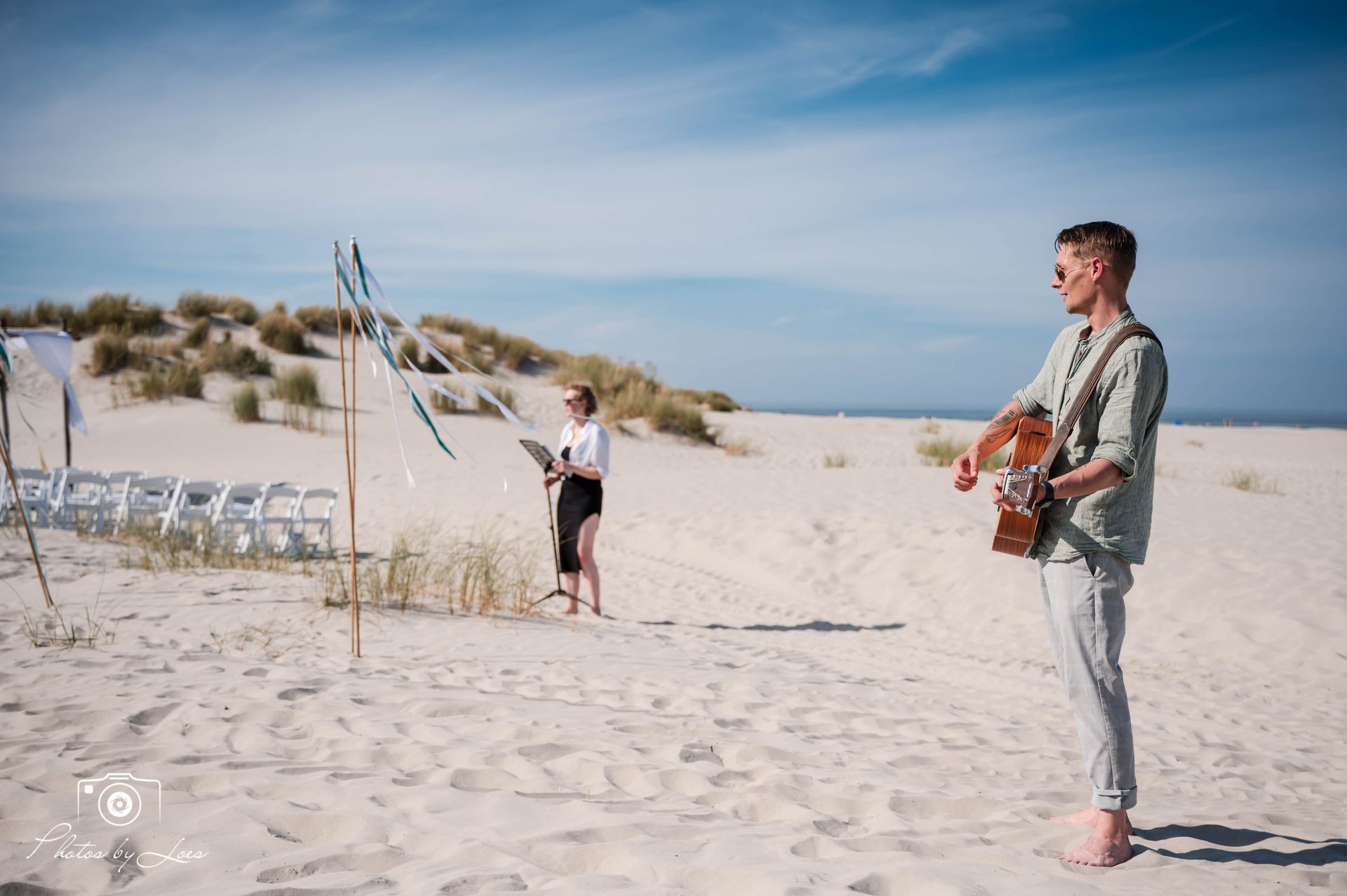 Een man speelt gitaar op het strand.