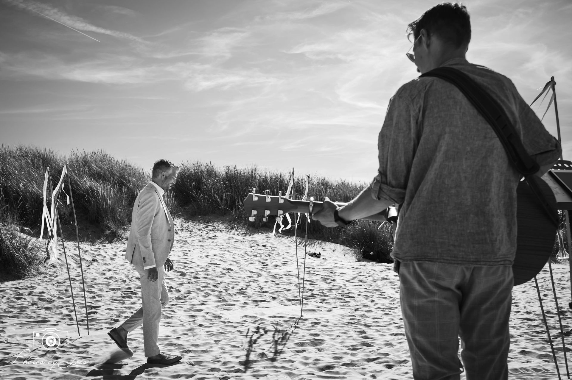 Een zwart-witfoto van twee mannen die op een strand lopen
