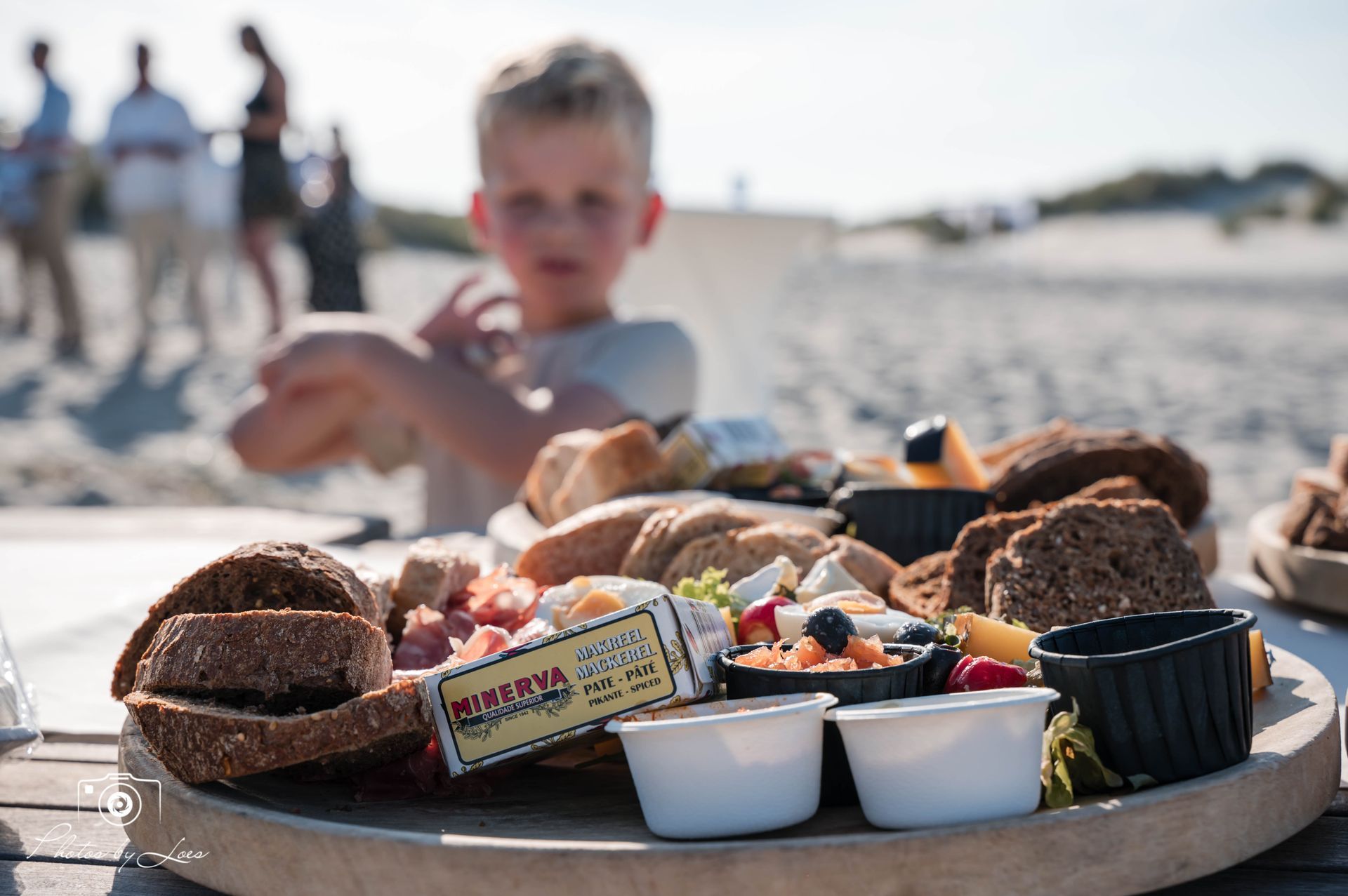 Een jonge jongen zit aan een tafel met een dienblad met eten.