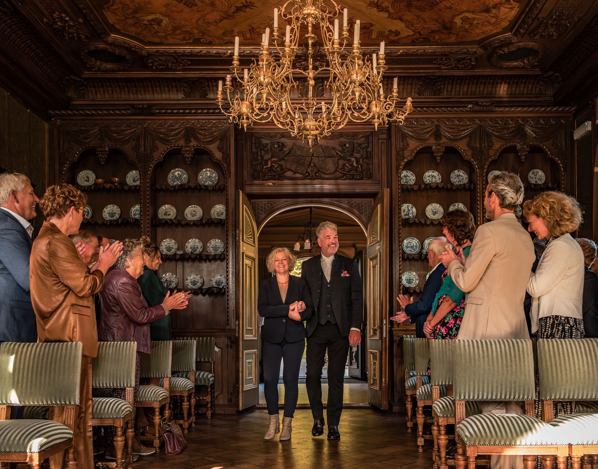 Een groep mensen staat in een kamer met een kroonluchter.