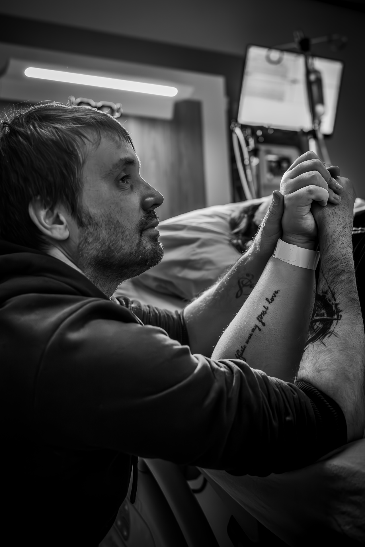 Een man houdt de hand van een vrouw vast in een ziekenhuisbed.