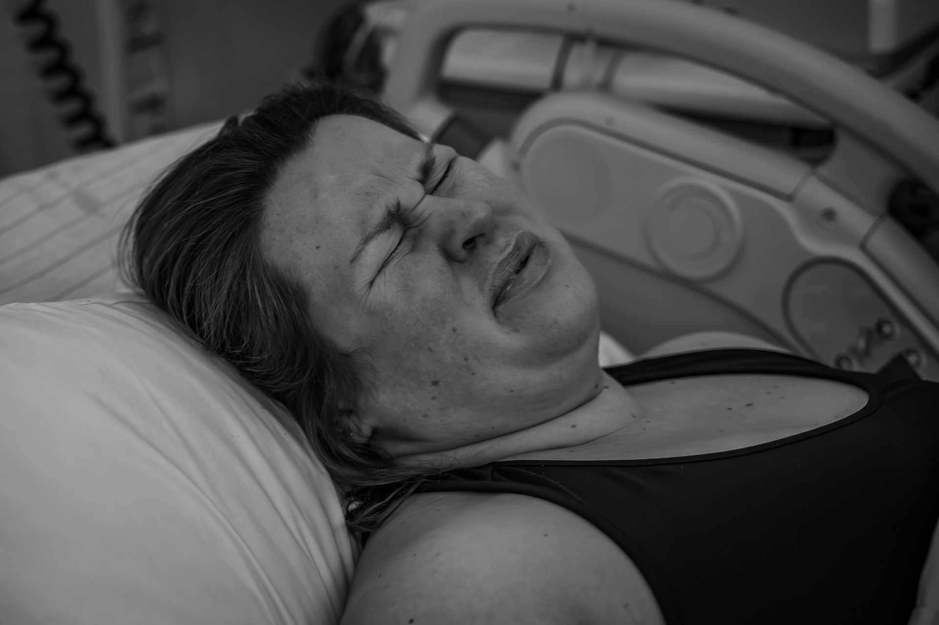 Een vrouw ligt met haar ogen dicht in een ziekenhuisbed.