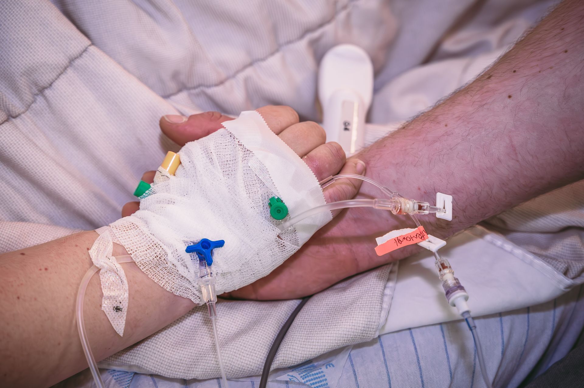 Een man en een vrouw houden elkaars hand vast in een ziekenhuisbed.