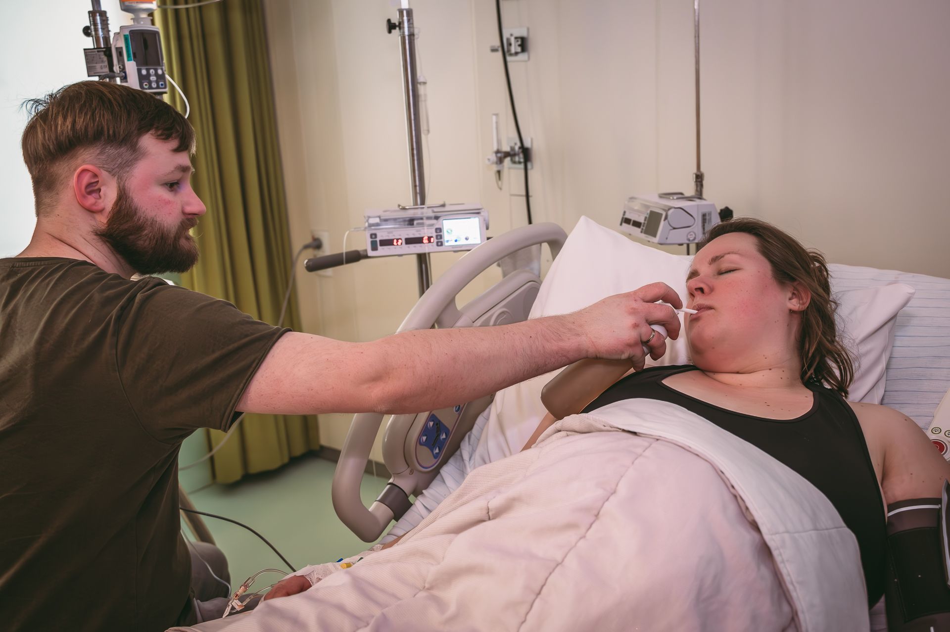 Een man voedt een vrouw in een ziekenhuisbed.