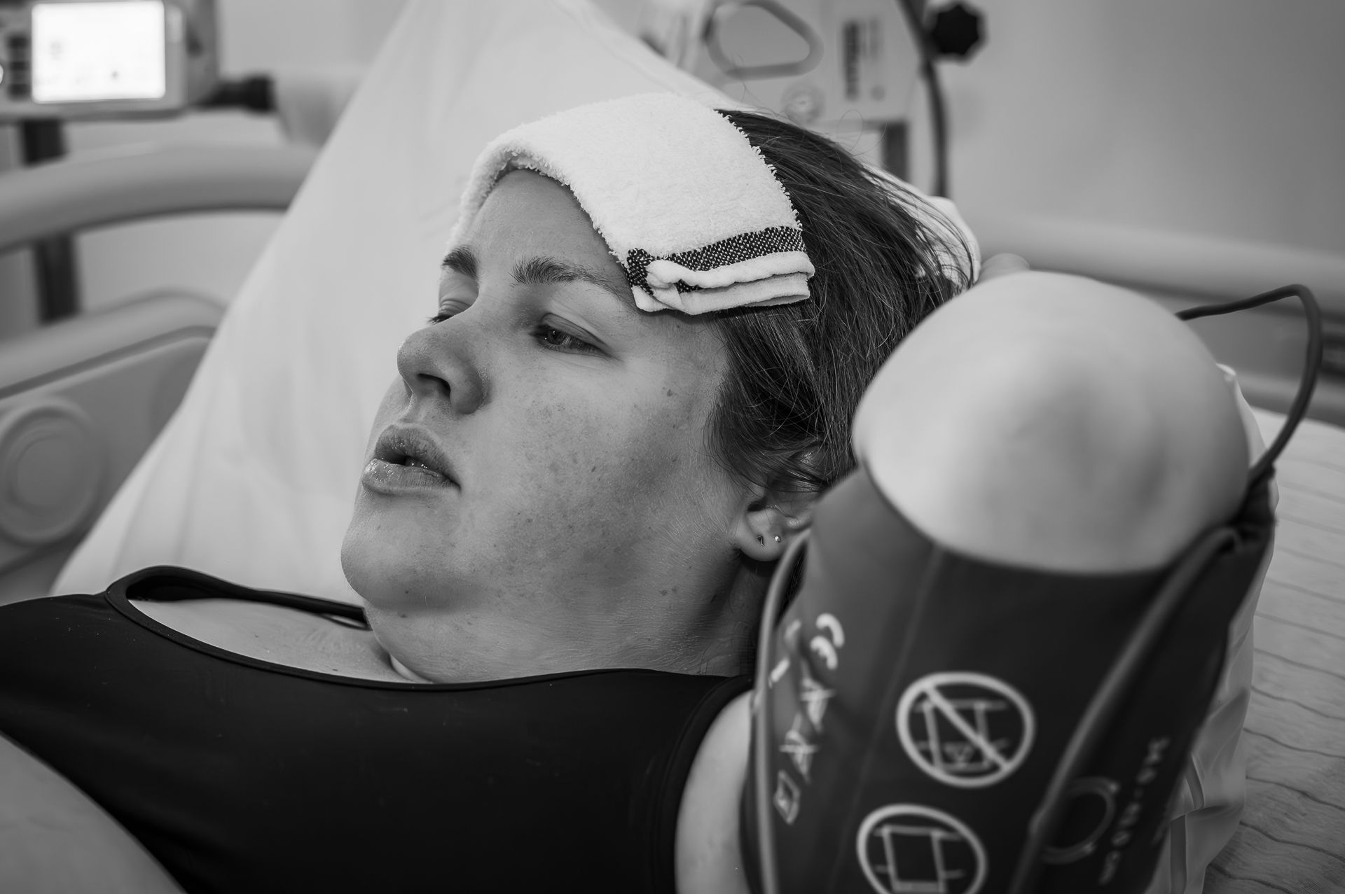 Een vrouw ligt in een ziekenhuisbed met een verband om haar hoofd.