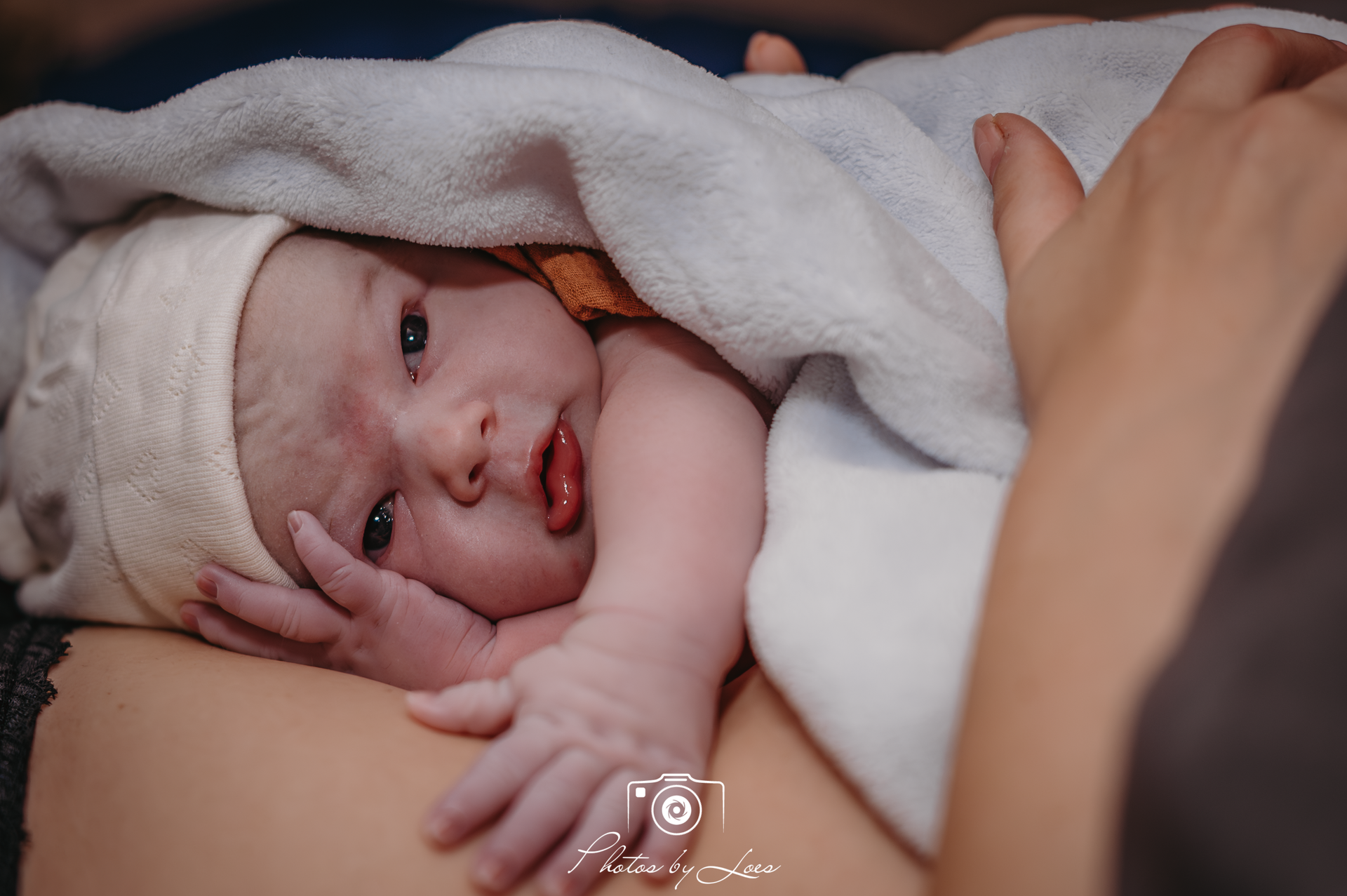 Een zwart-witfoto van een persoon die een pasgeboren baby vasthoudt.