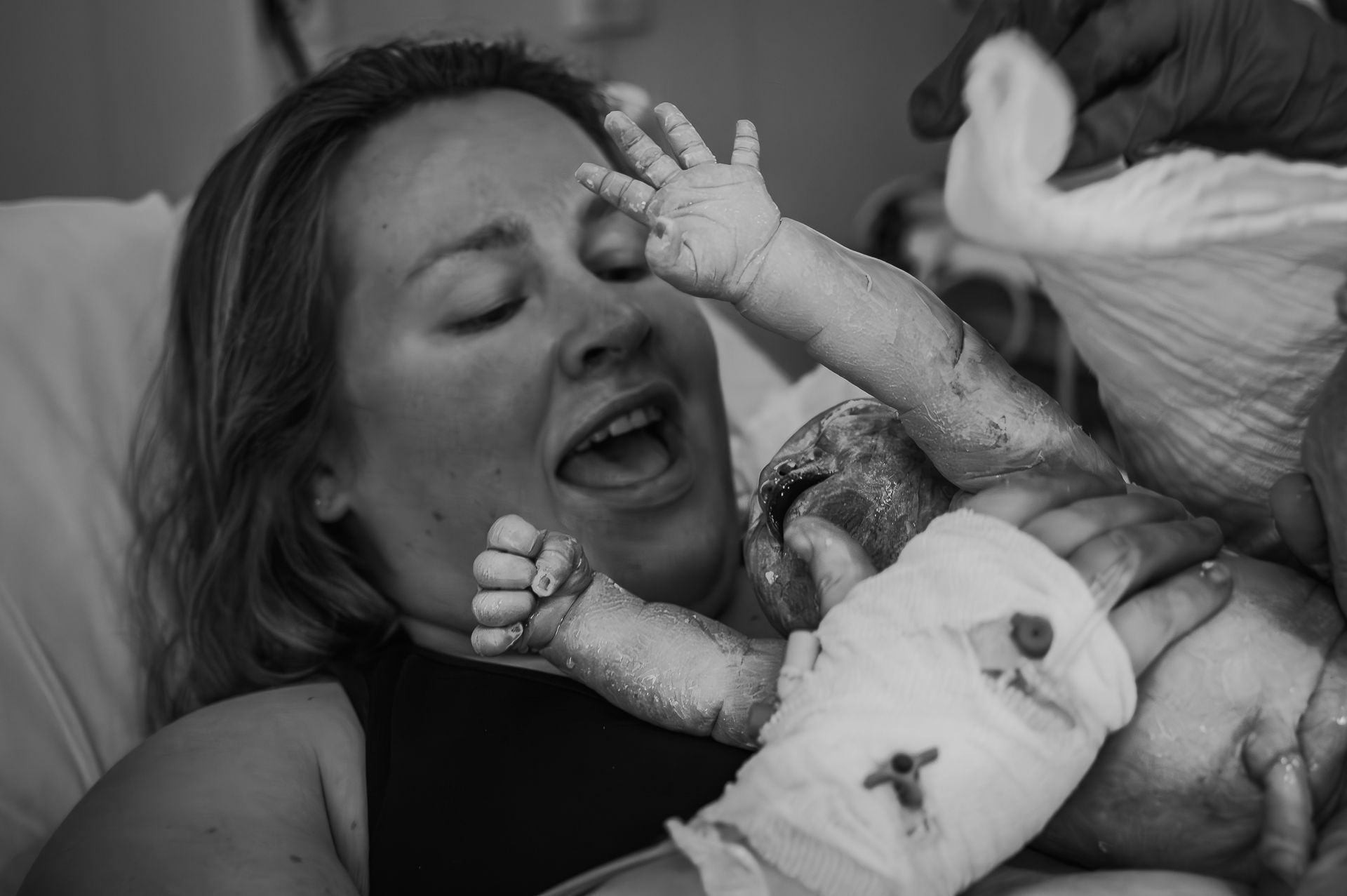 Een zwart-witfoto van een vrouw die een pasgeboren baby vasthoudt.