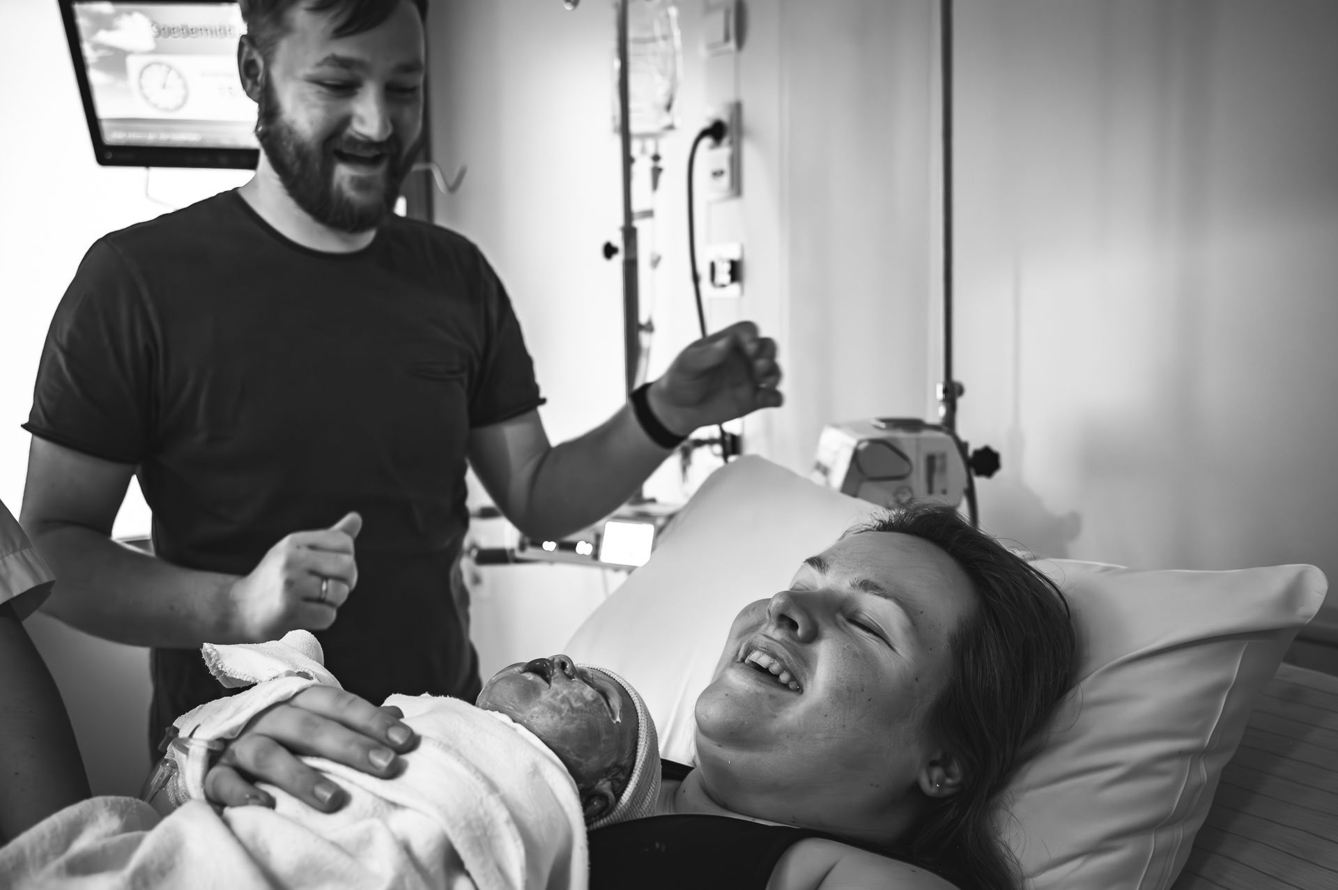 Een man en een vrouw houden een pasgeboren baby vast in een ziekenhuisbed.