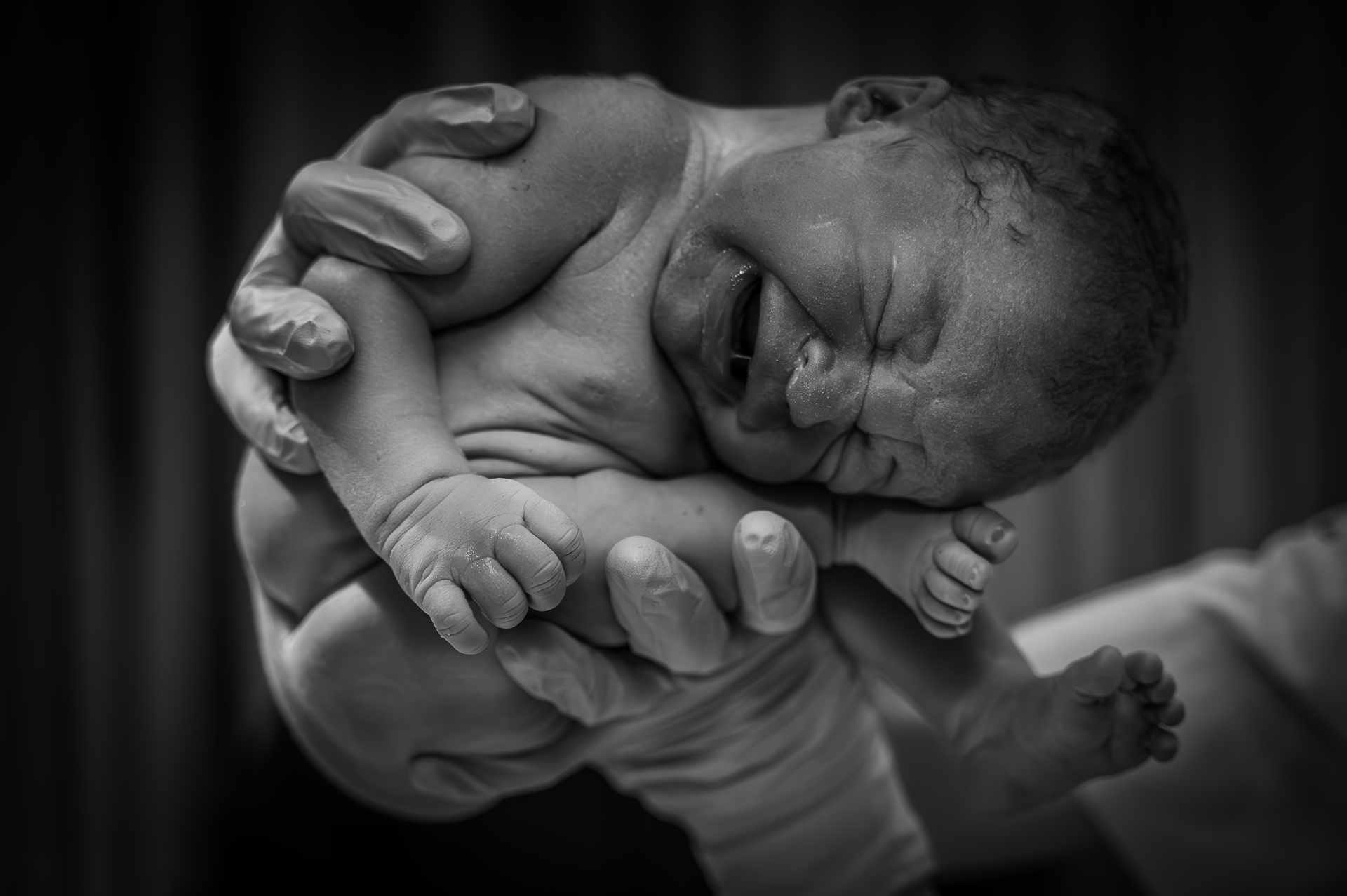 Een zwart-witfoto van een persoon die een pasgeboren baby vasthoudt.