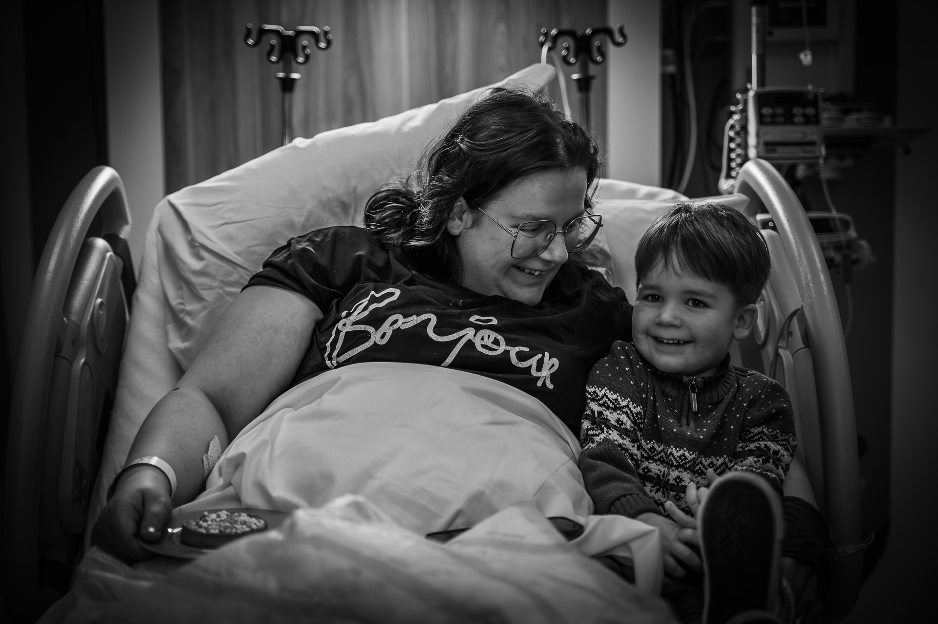 Een vrouw ligt met een kind in een ziekenhuisbed.