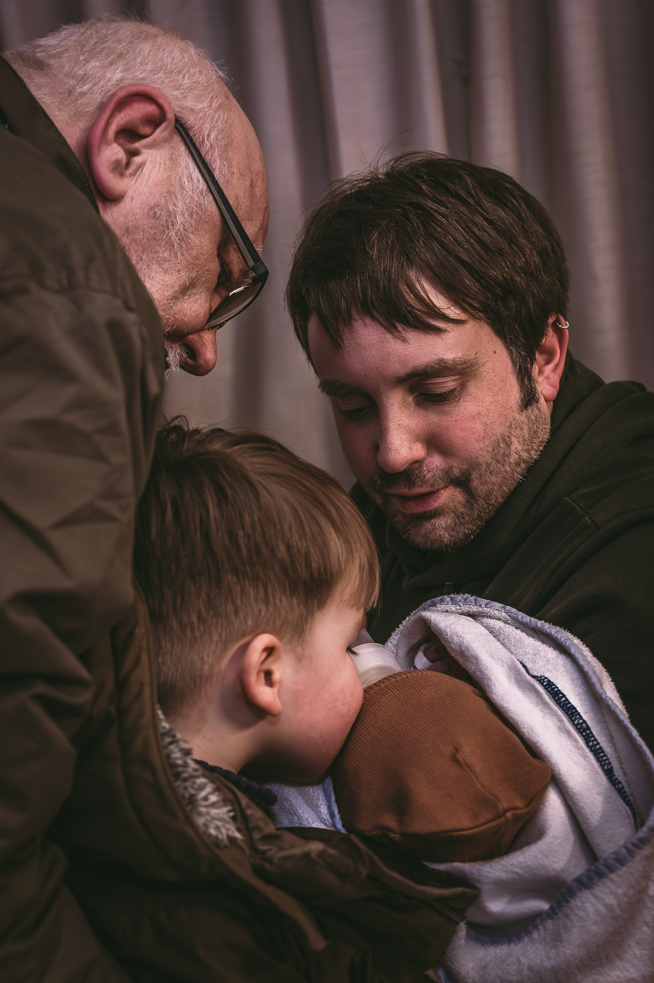 Twee mannen houden een jongetje in hun armen.