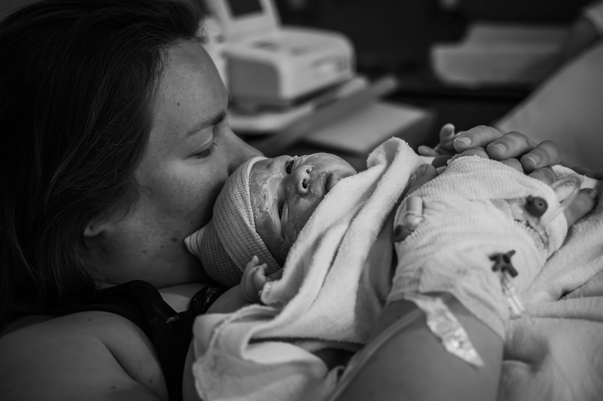 Een vrouw houdt een pasgeboren baby vast in een ziekenhuisbed.