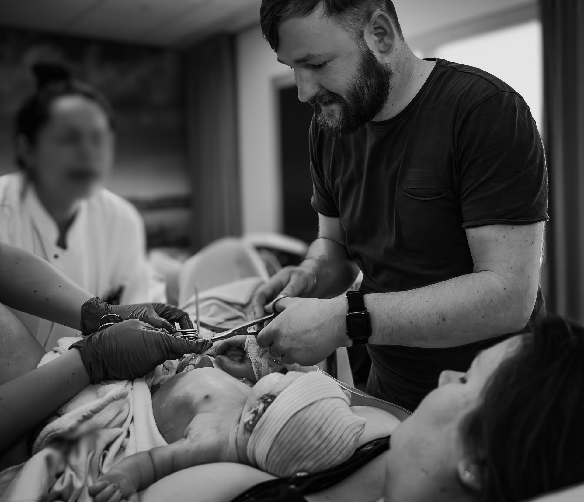 Een man knipt de navelstreng van een baby door in een ziekenhuis.