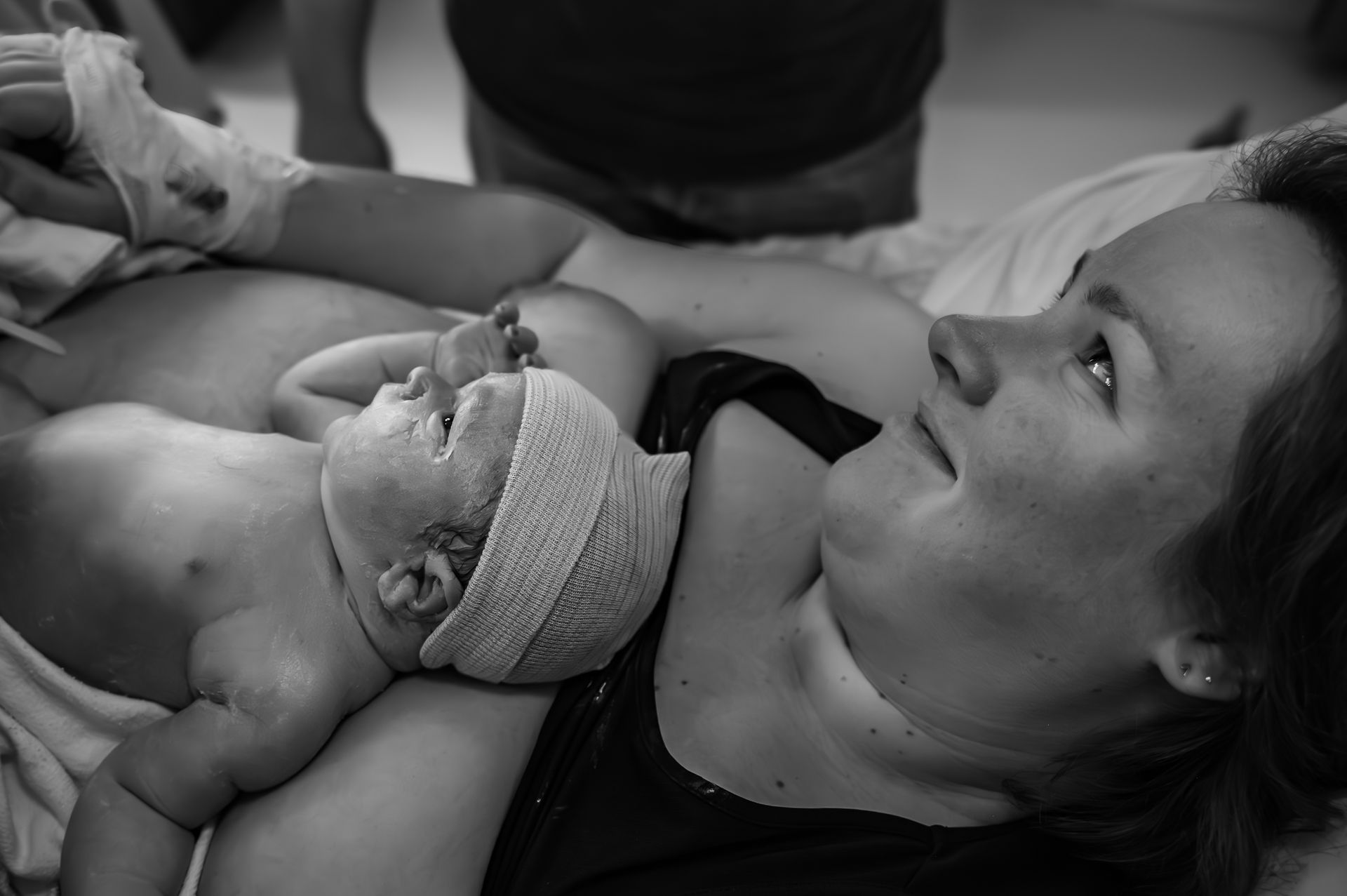 Een zwart-witfoto van een vrouw die een pasgeboren baby vasthoudt.