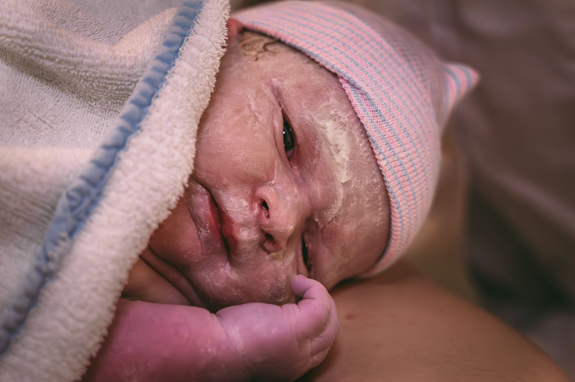 Een close-up van een pasgeboren baby met een roze mutsje.