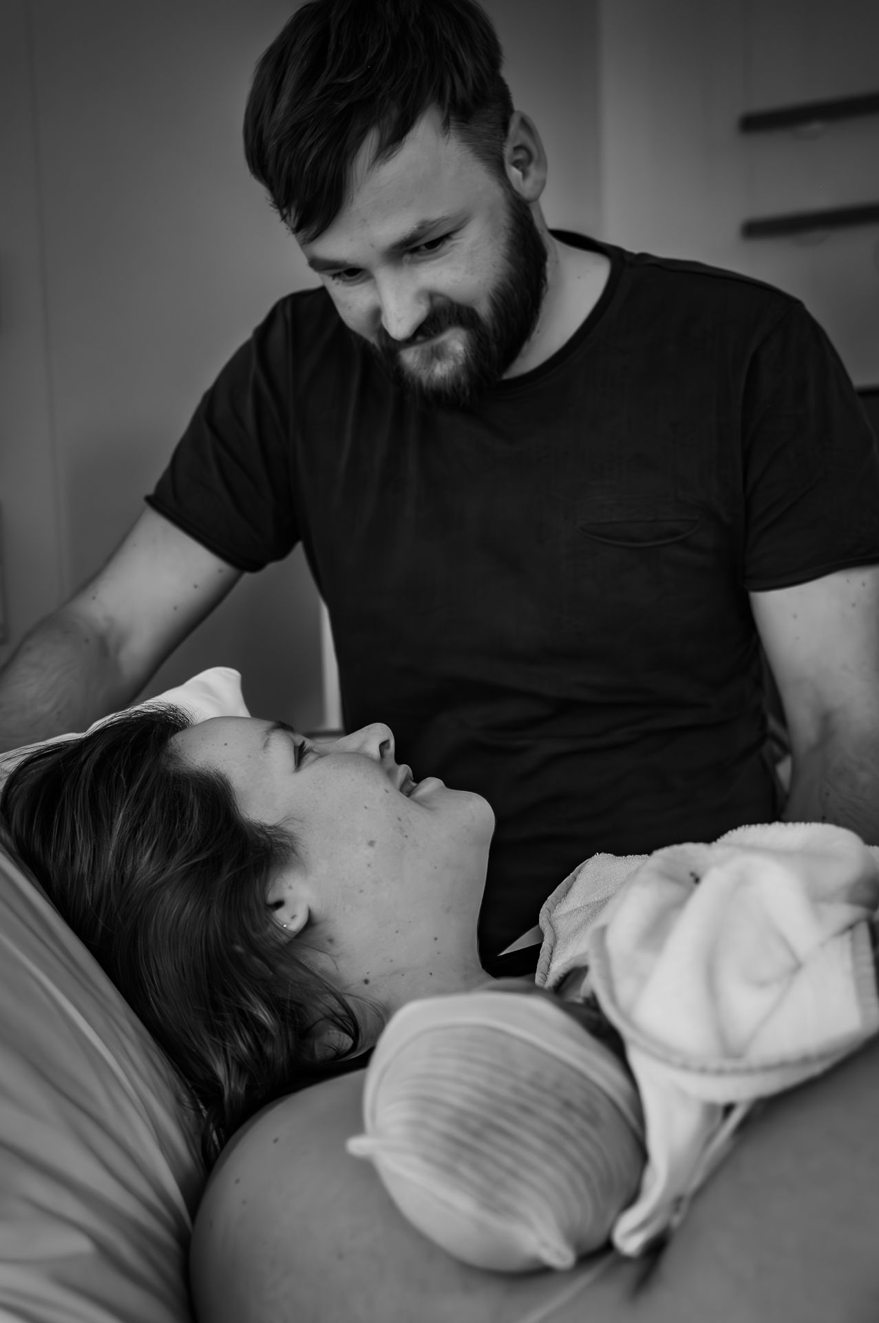 Op een zwart-witfoto houden een man en een vrouw een pasgeboren baby vast.