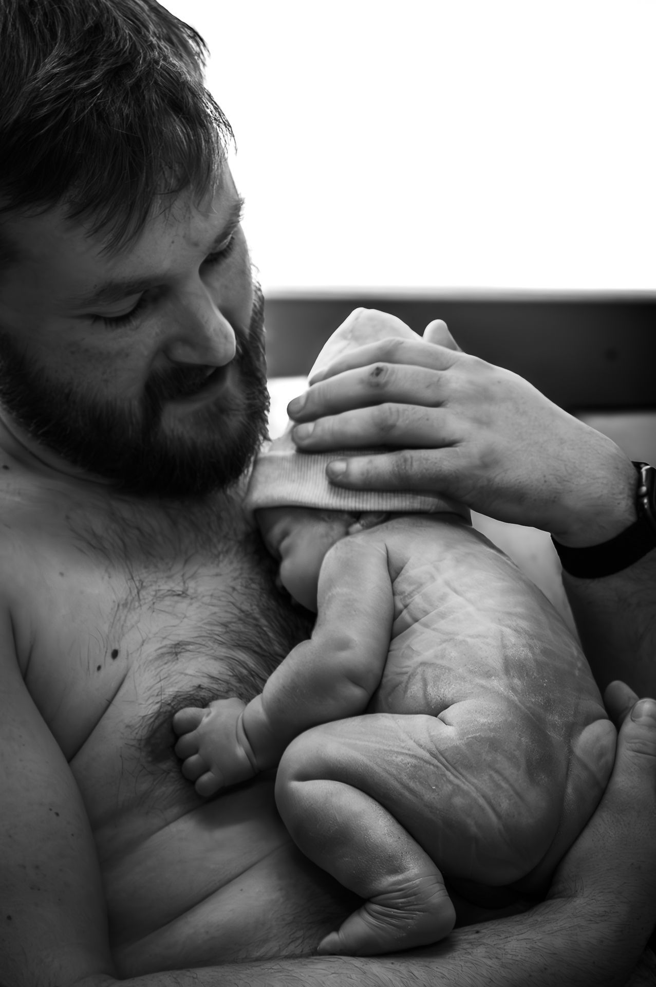 Een man houdt een pasgeboren baby in zijn armen.