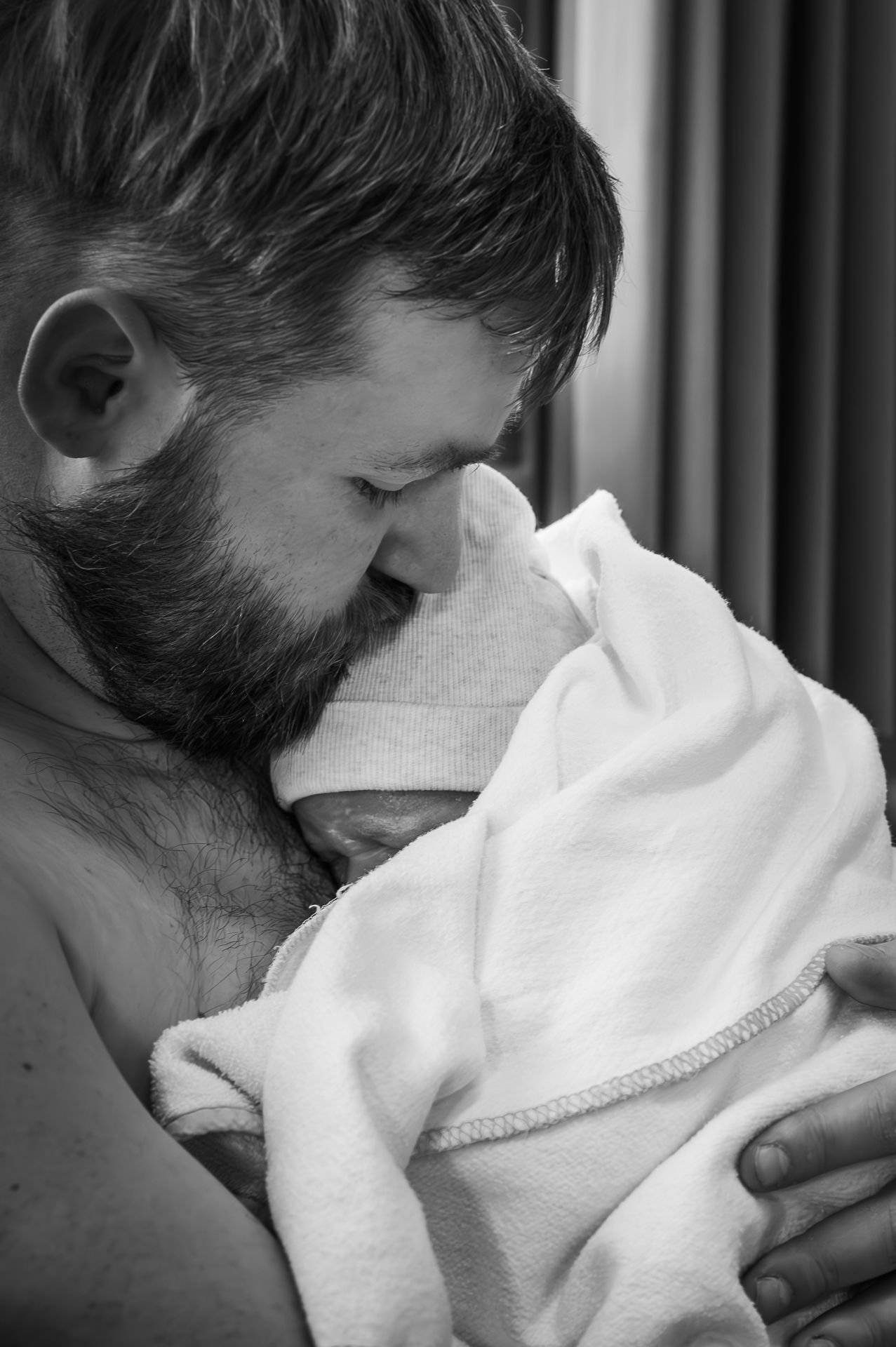 Op een zwart-witfoto houdt een man een pasgeboren baby in zijn armen.