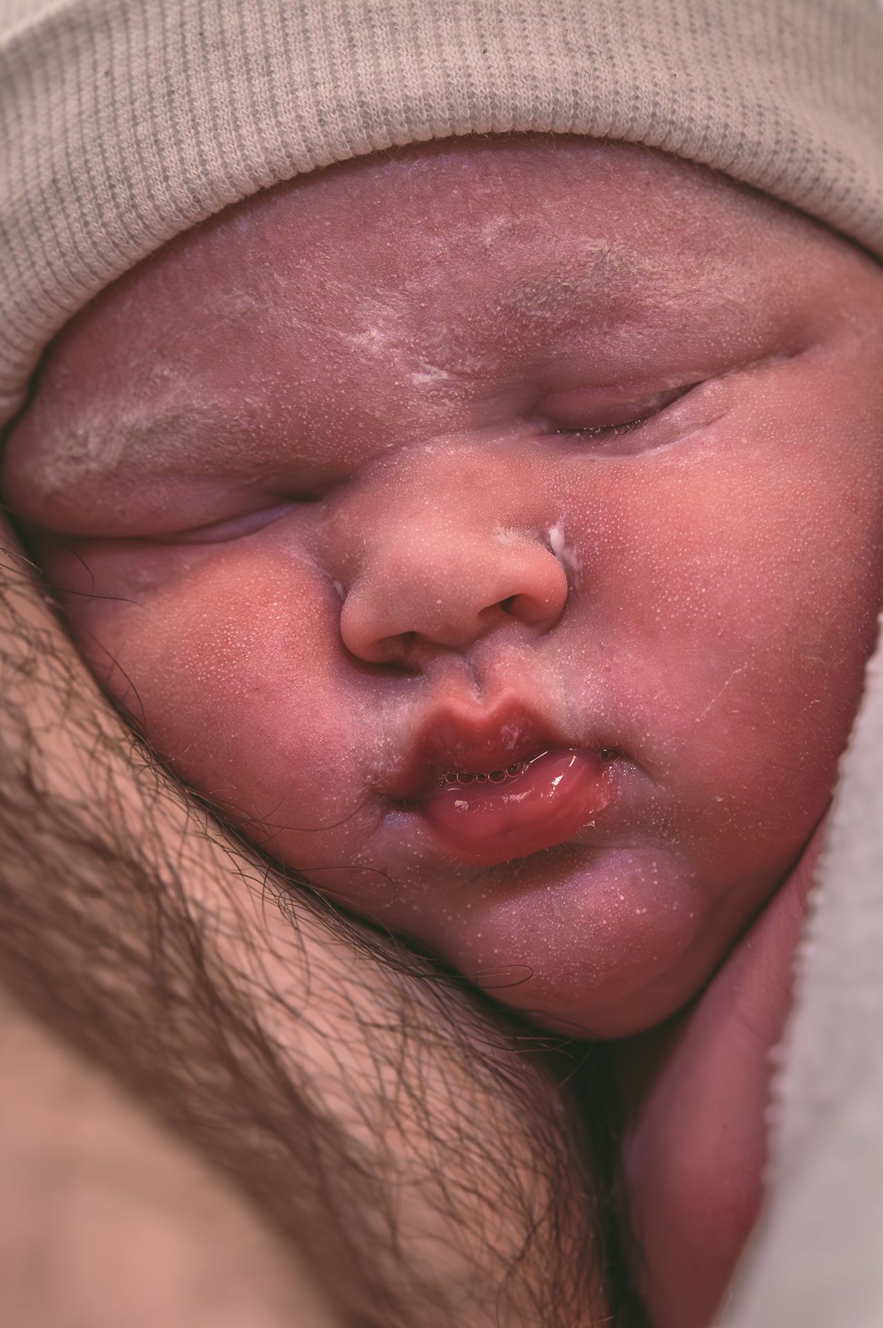 Een close-up van een pasgeboren baby die slaapt in de armen van een persoon.