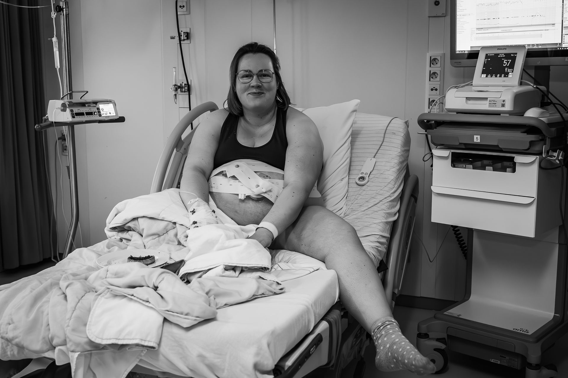 Een zwangere vrouw zit in een ziekenhuisbed.