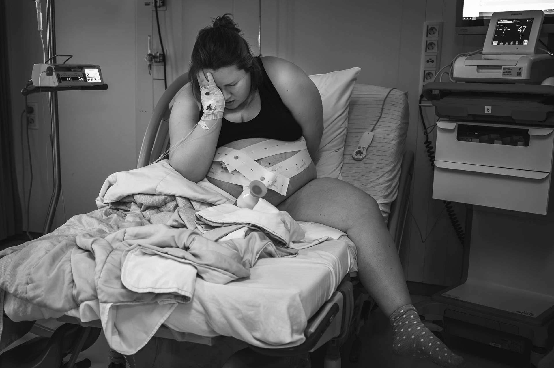 Een zwangere vrouw ligt in een ziekenhuisbed met een baby in haar armen.