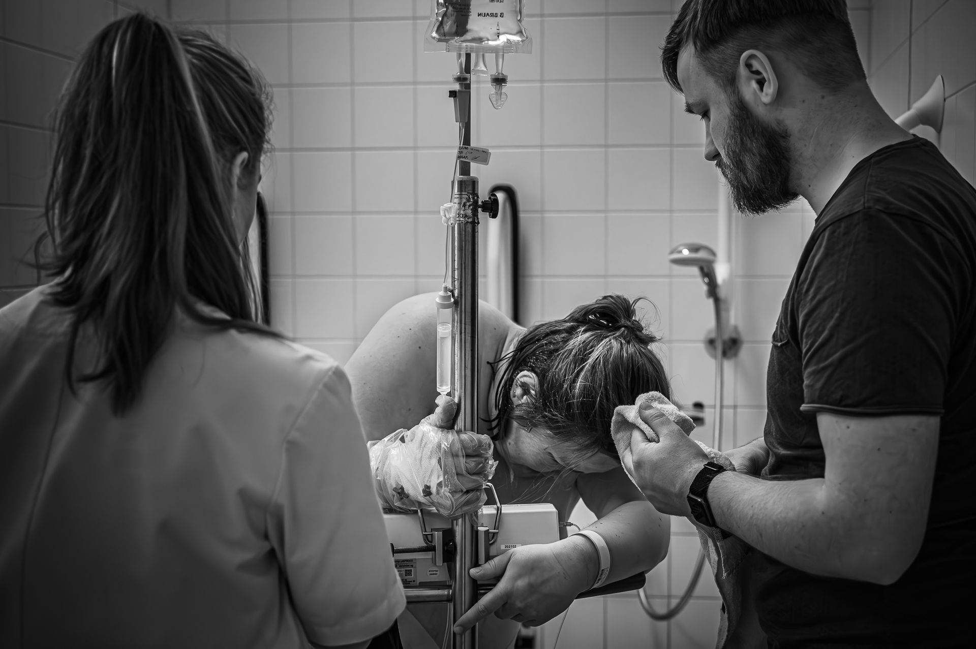 Een zwart-witfoto van een vrouw die in een ziekenhuis bevalt.