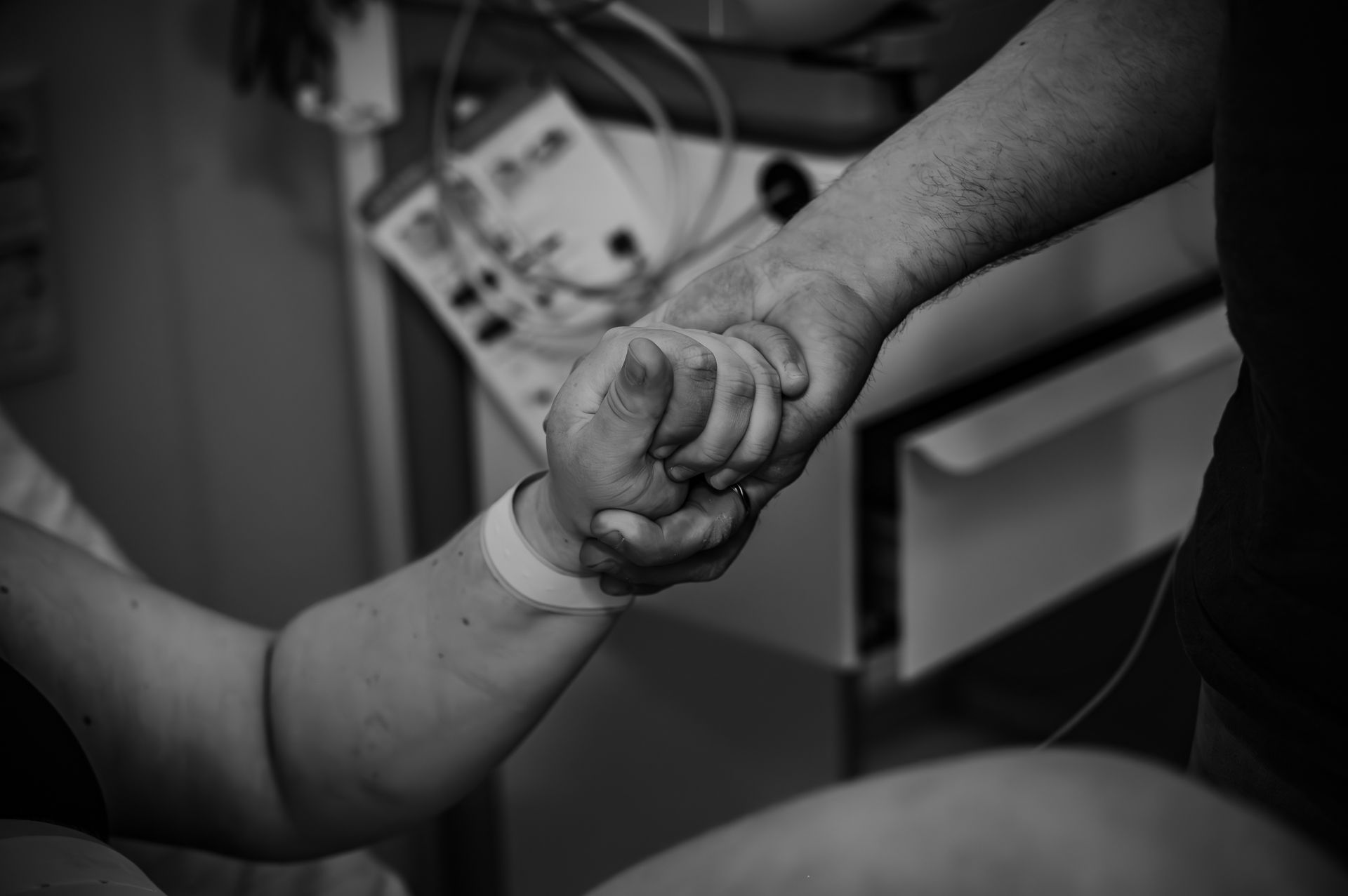 Een zwart-witfoto van een persoon die de hand van een andere persoon vasthoudt.