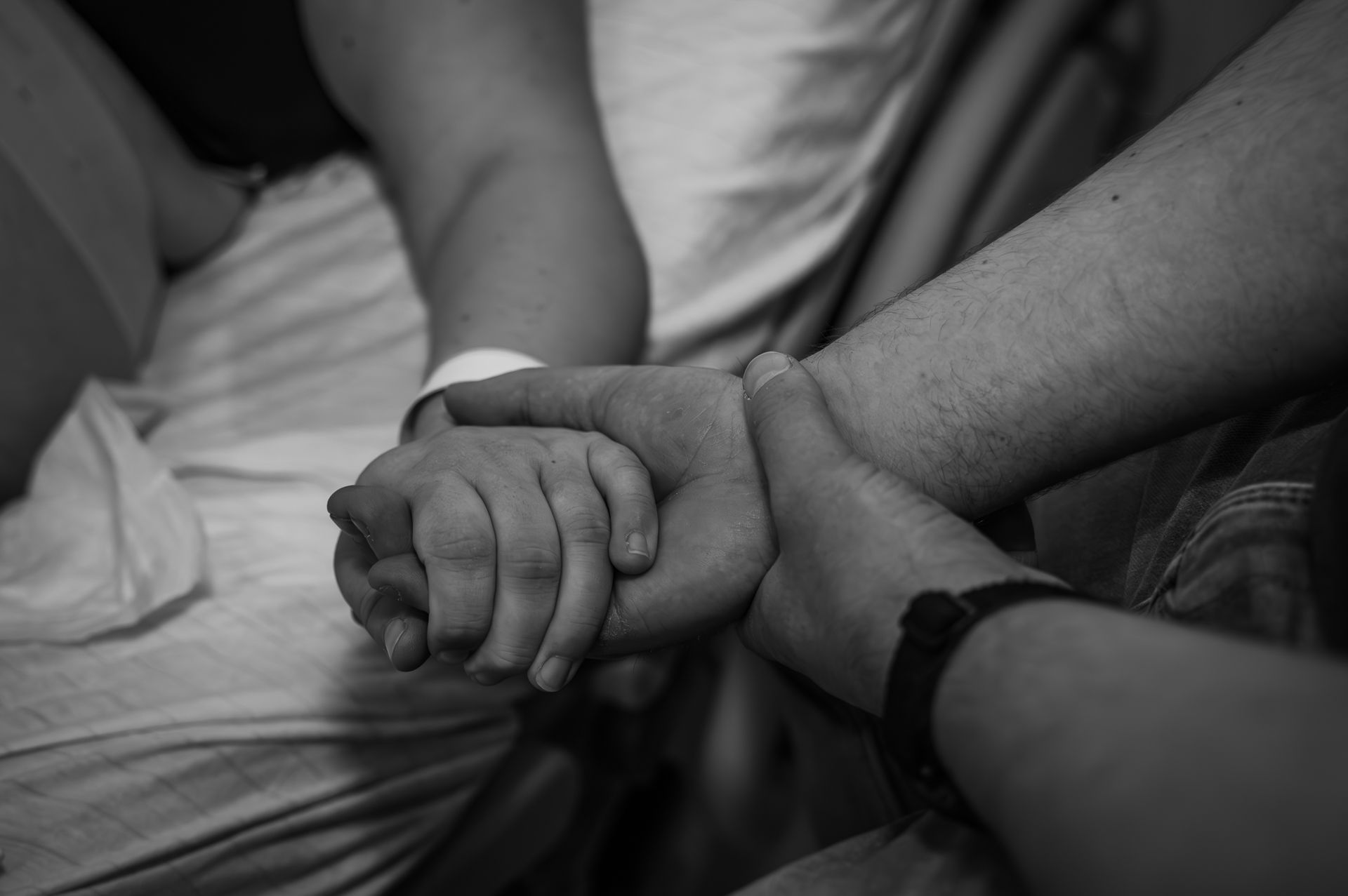 Een groep mensen houdt elkaars handen vast op een zwart-witfoto.