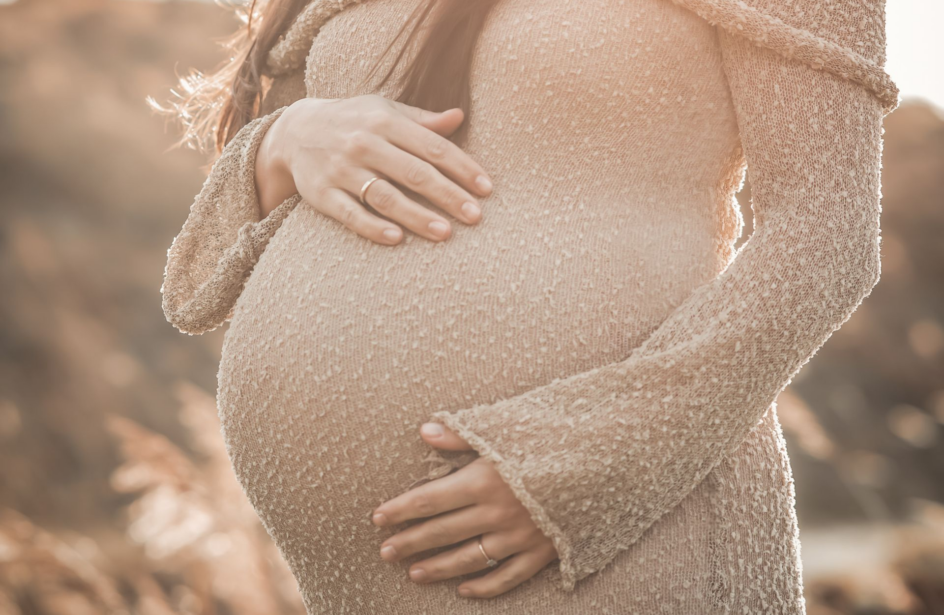 Een zwart-witfoto van een zwangere vrouw en een man die in het water lopen.