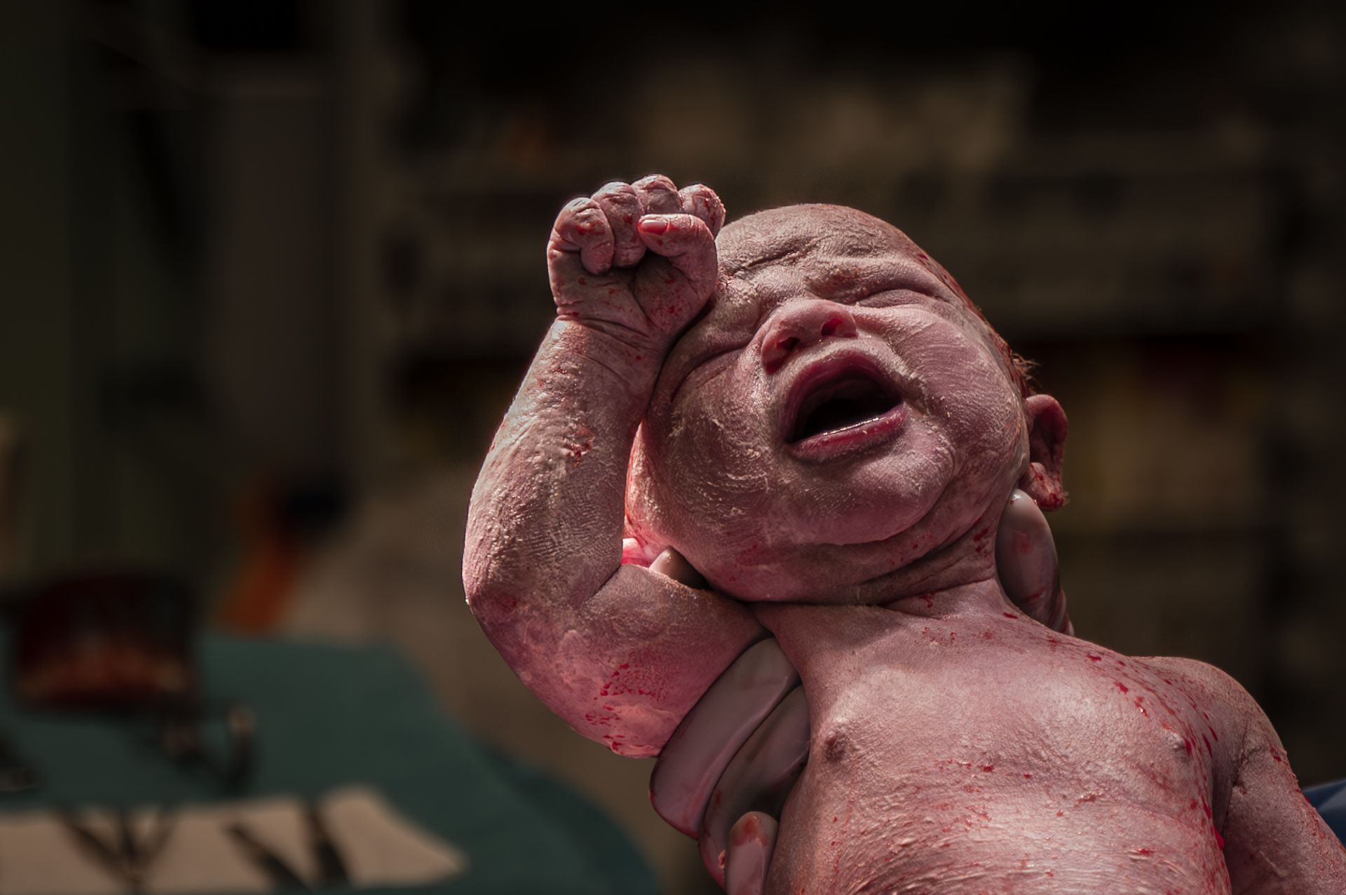 Een pasgeboren baby huilt in een donkere kamer.