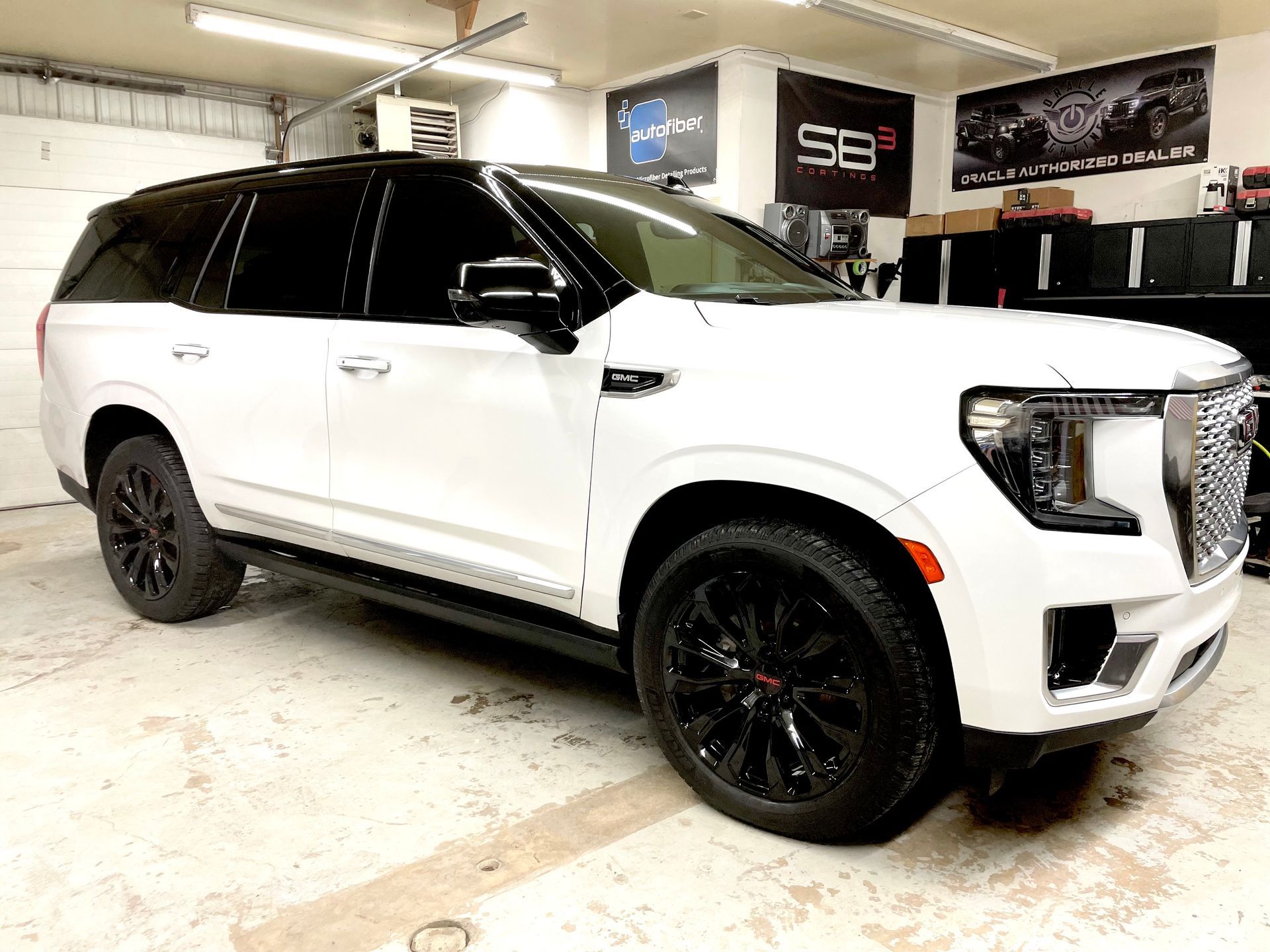 A white suv is parked in a garage with black wheels.