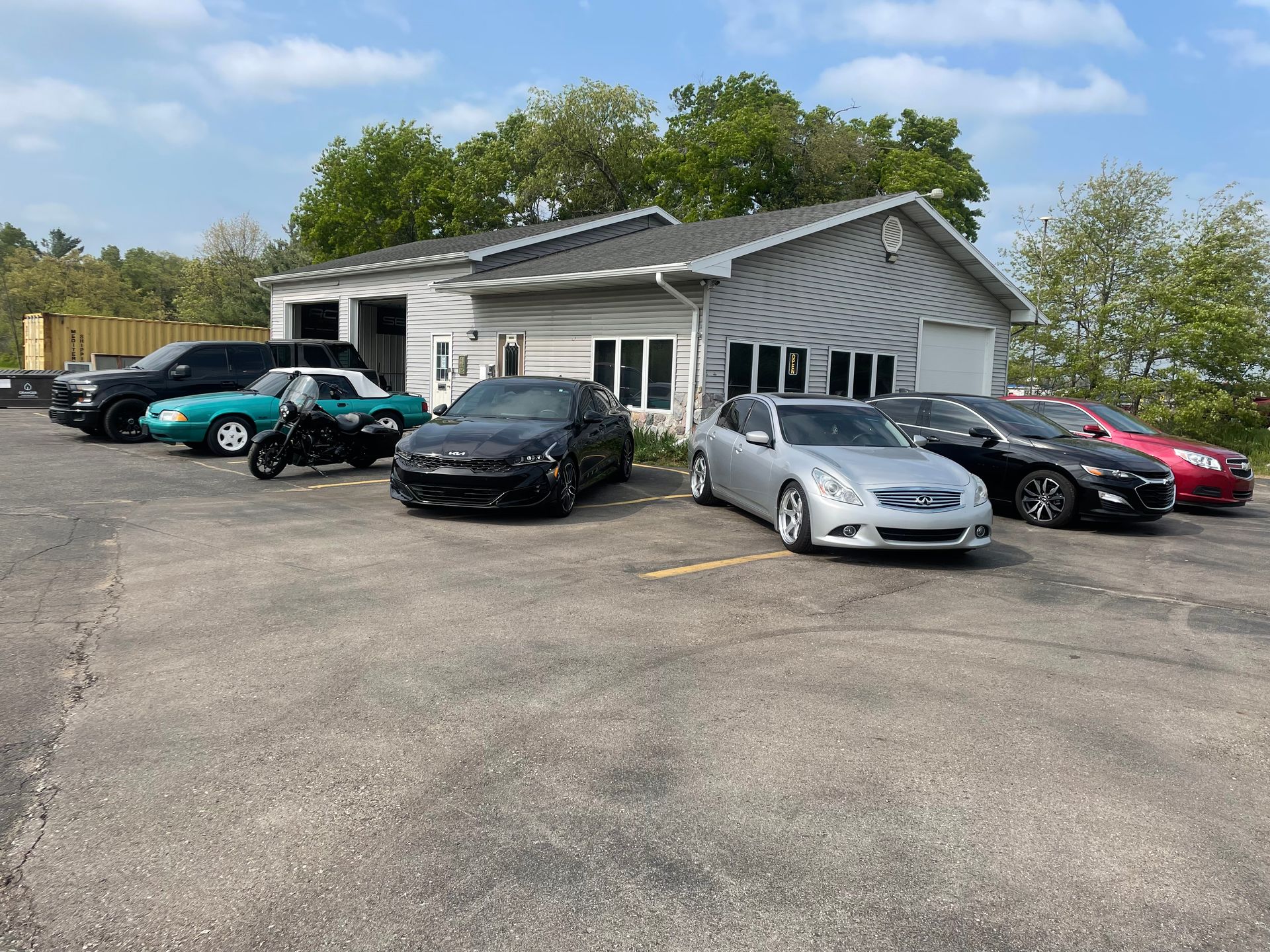 A row of cars are parked in front of a garage.