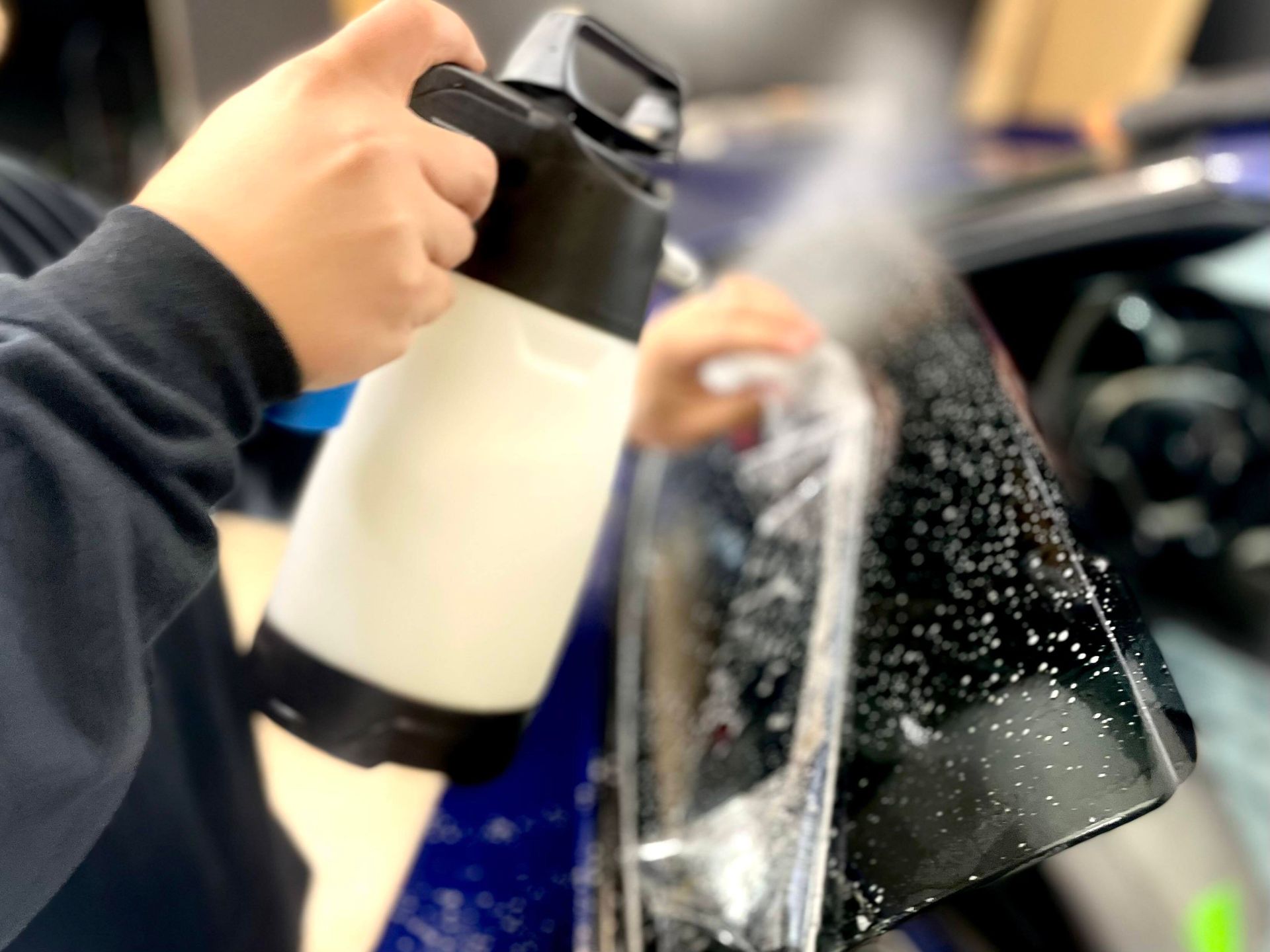 A person is spraying a car with a spray bottle.