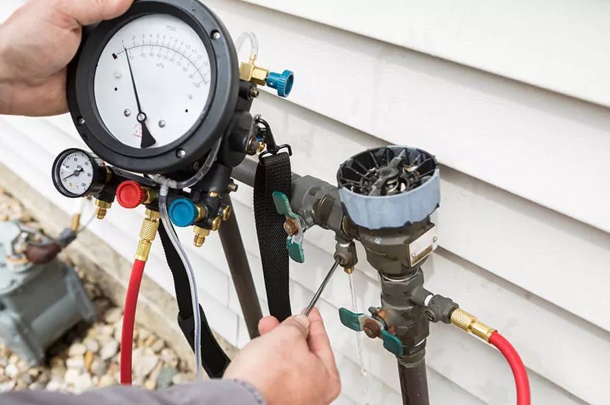 A person is holding a pressure gauge next to a pipe.