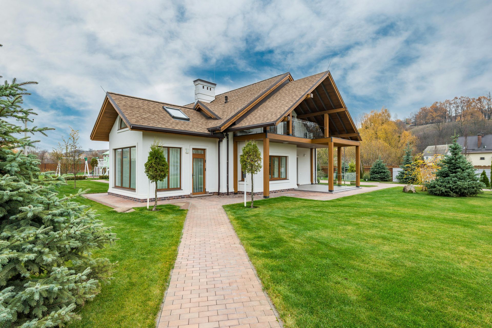 White house with brown roof and trim, brick walkway on a green lawn.