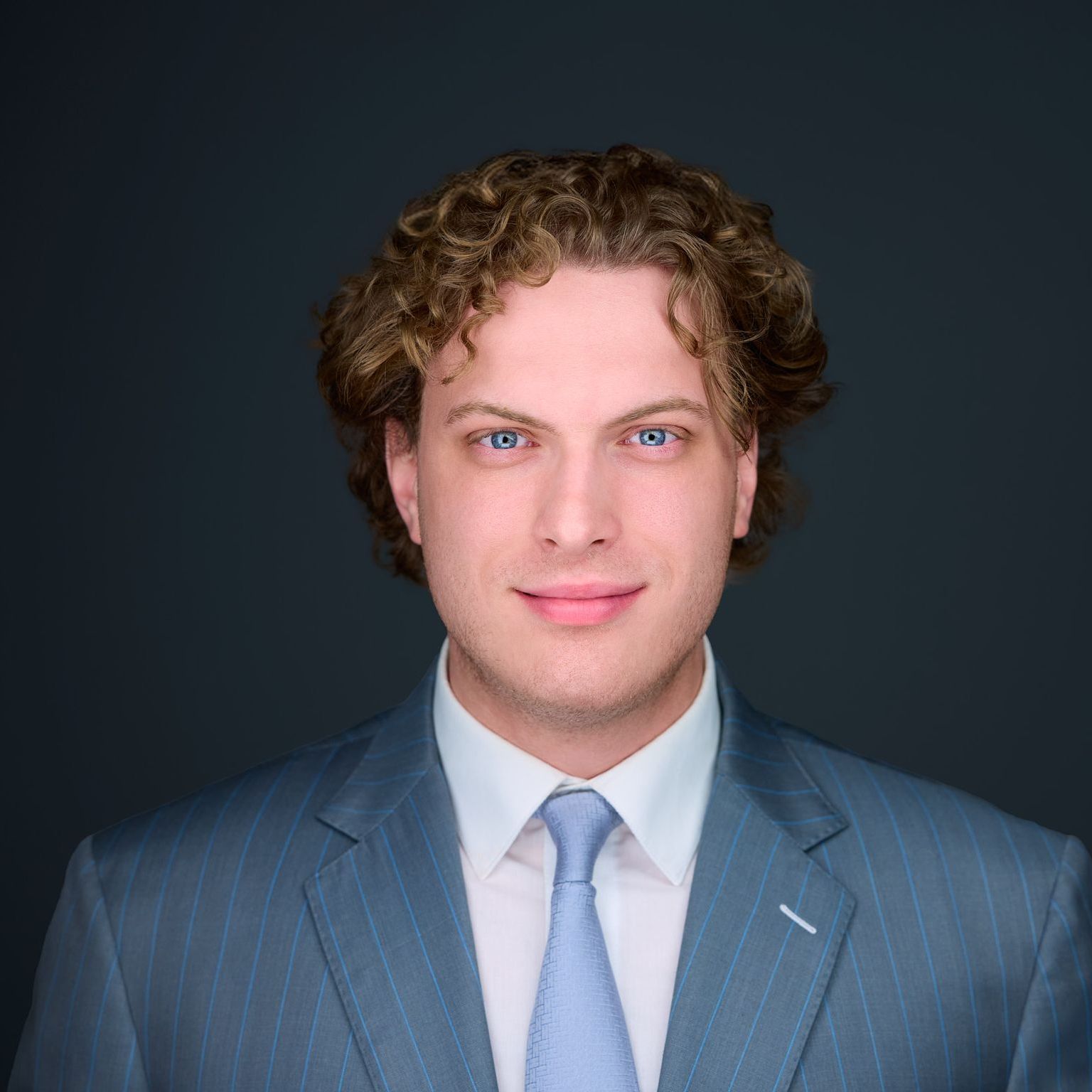 A woman is wearing a striped jacket and smiling for the camera.