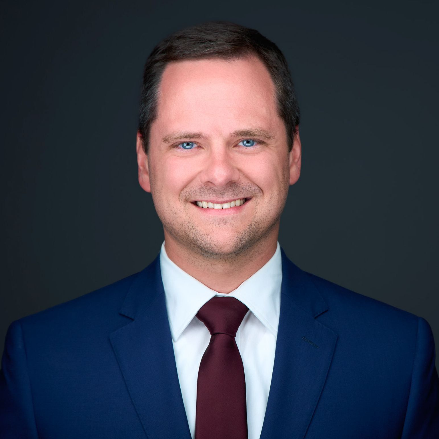 A man in a suit and tie is smiling for the camera.