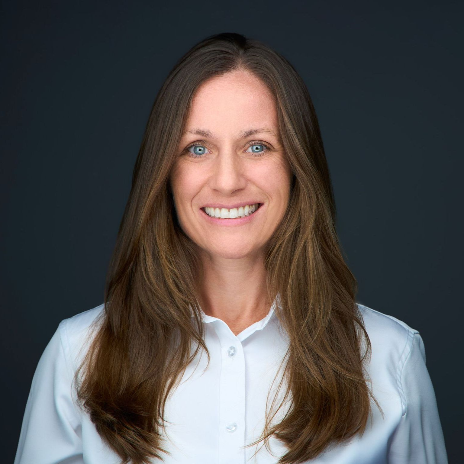 Jessica Holfert A woman with long brown hair is smiling for the camera while wearing a white shirt.
